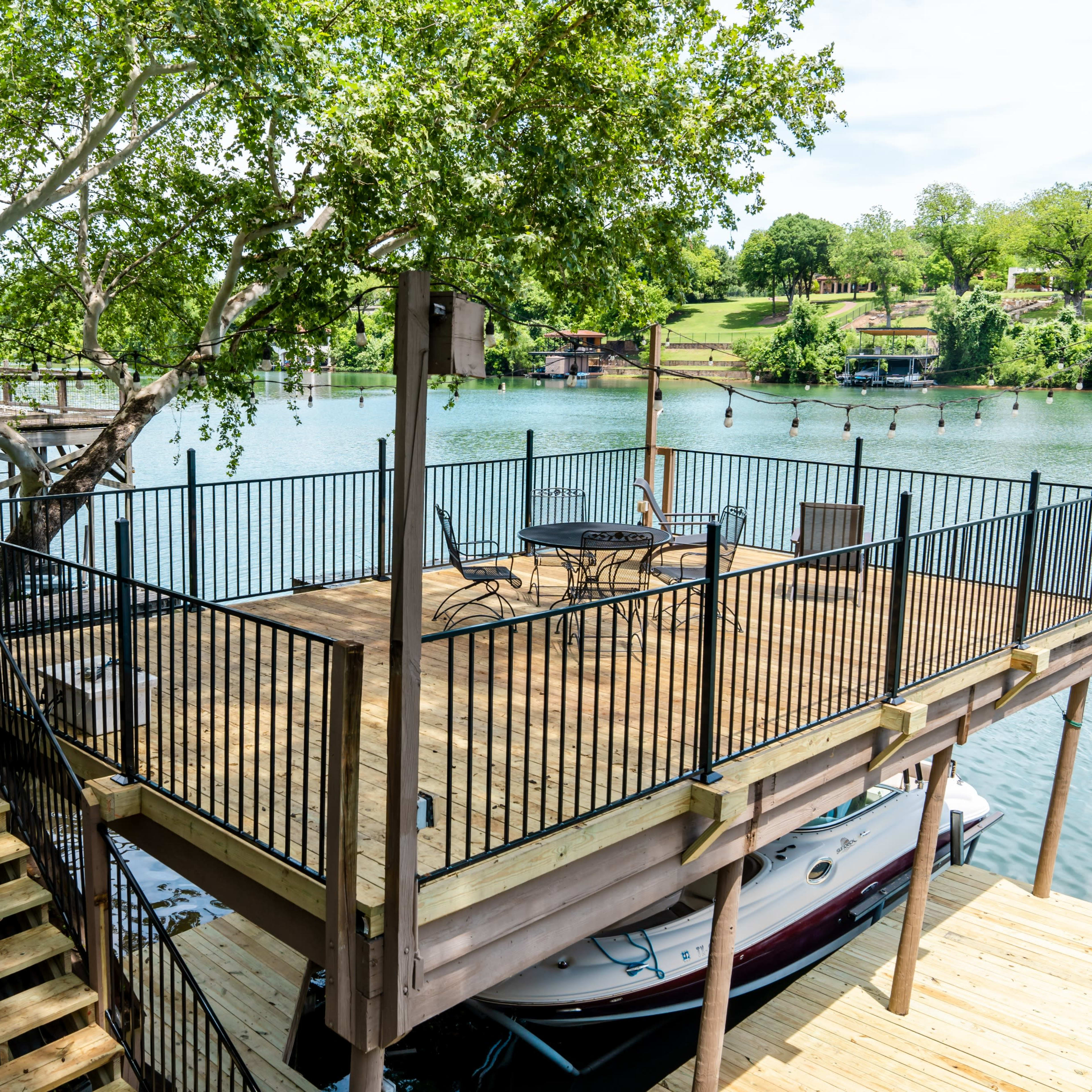 A riverside dock with a wooden deck, a set of stairs, and a boat moored below.
