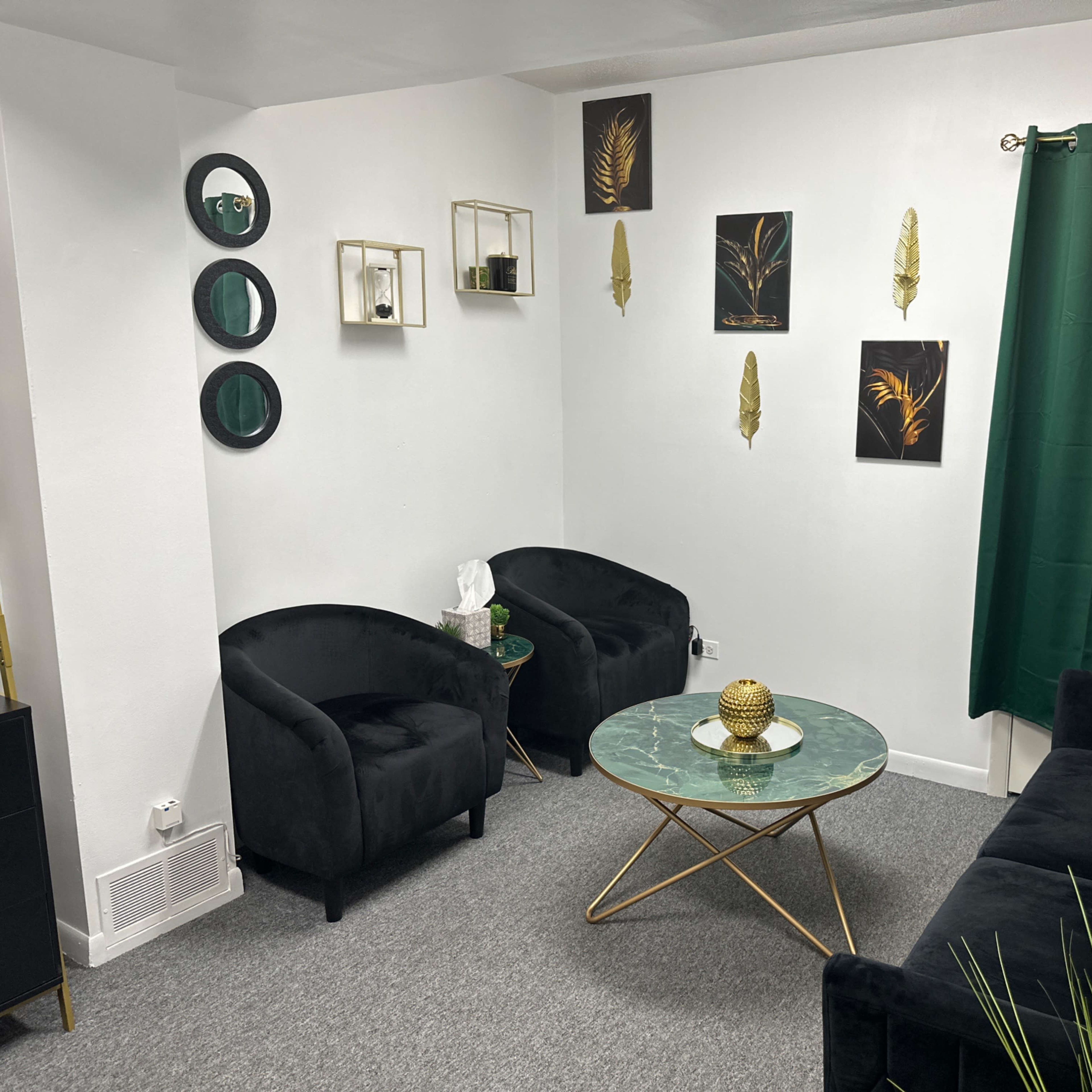 A modern living room with black furniture, a green curtain, gold accents, and wall art featuring plant themes.