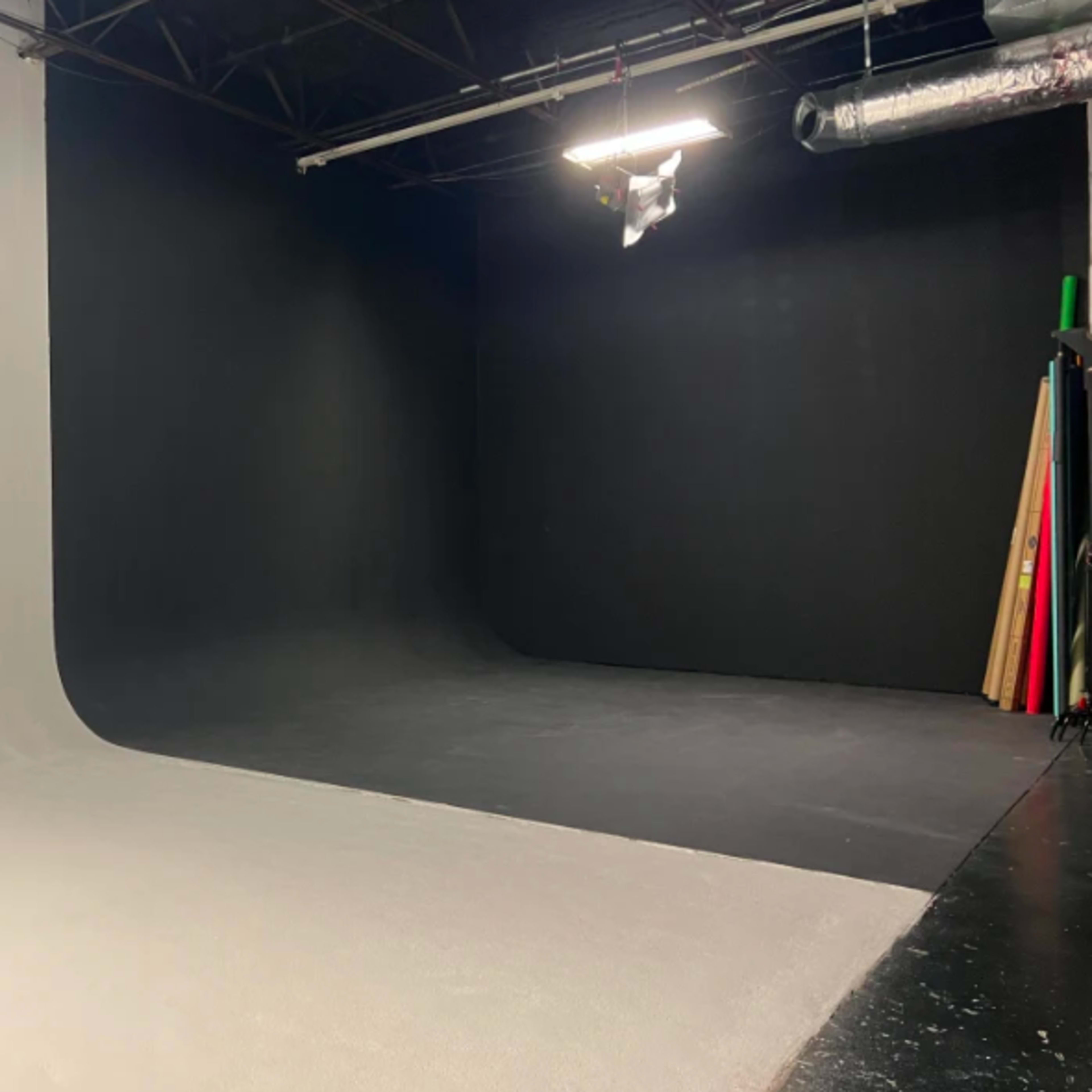 A photography studio with a large, curved white backdrop on one side and a dark black backdrop on the other.