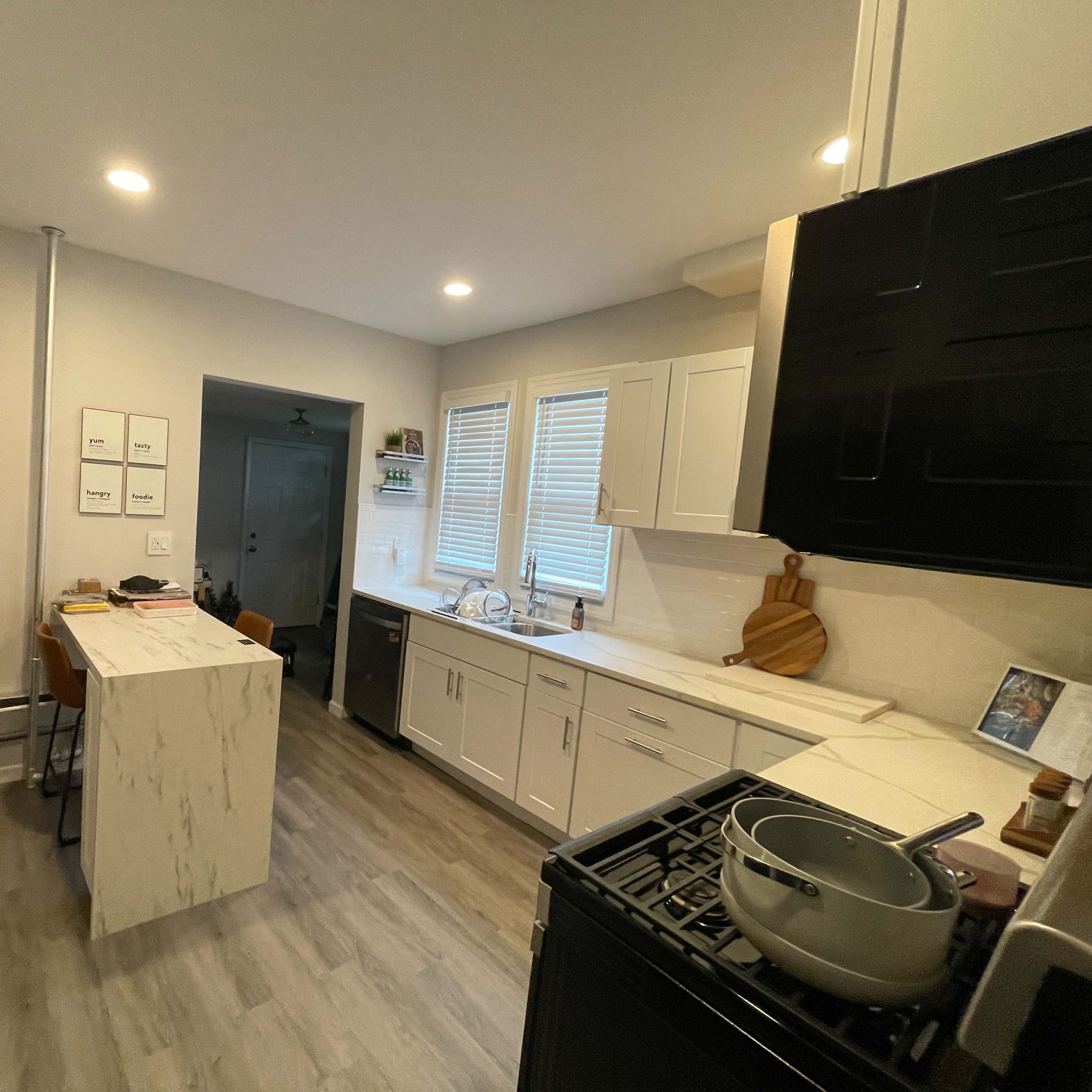 A modern kitchen featuring a central island with a marble surface, white cabinetry, and a window that provides natural light.
