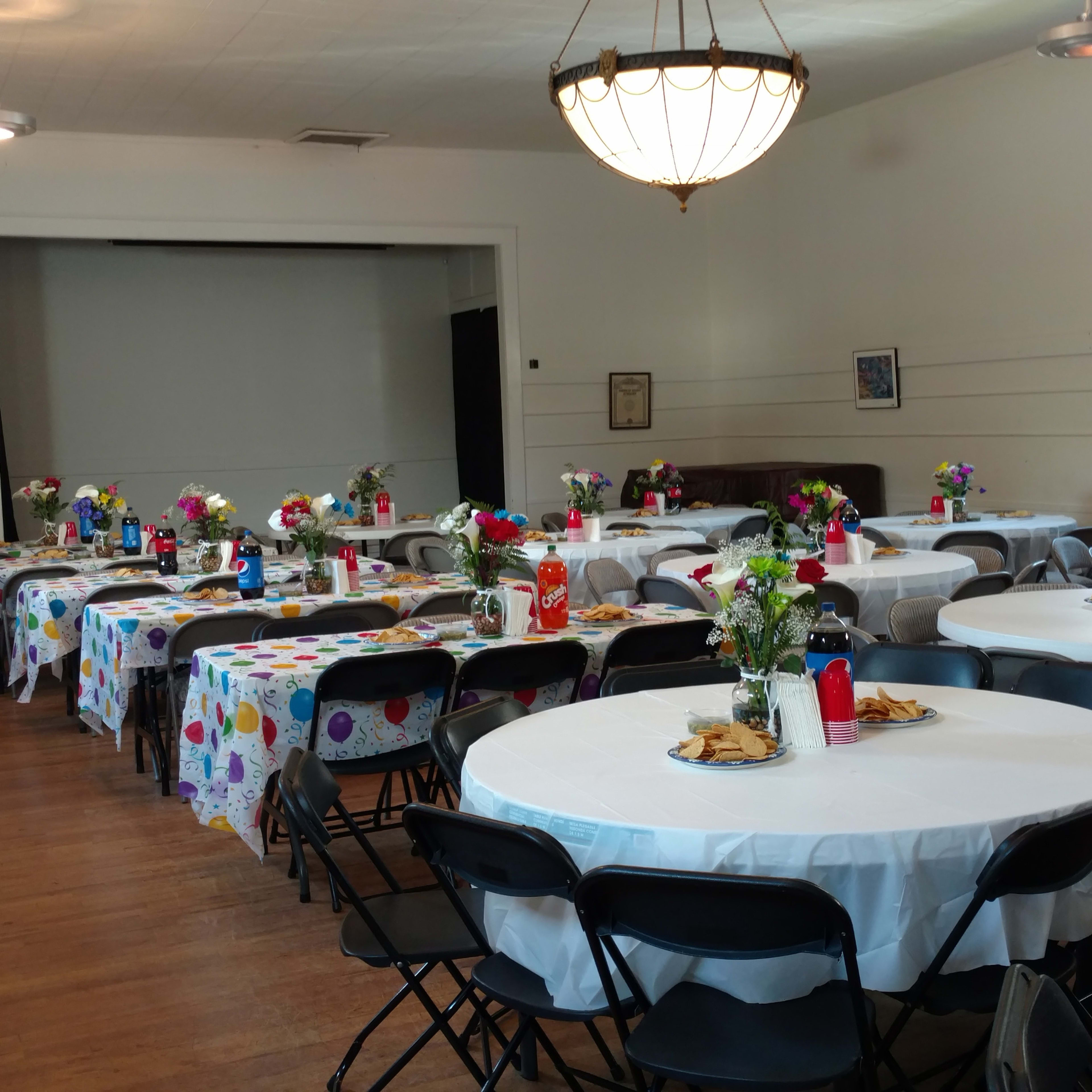 A spacious banquet hall arranged with several round tables covered in polka-dotted tablecloths, each set with floral centerpieces and place settings.