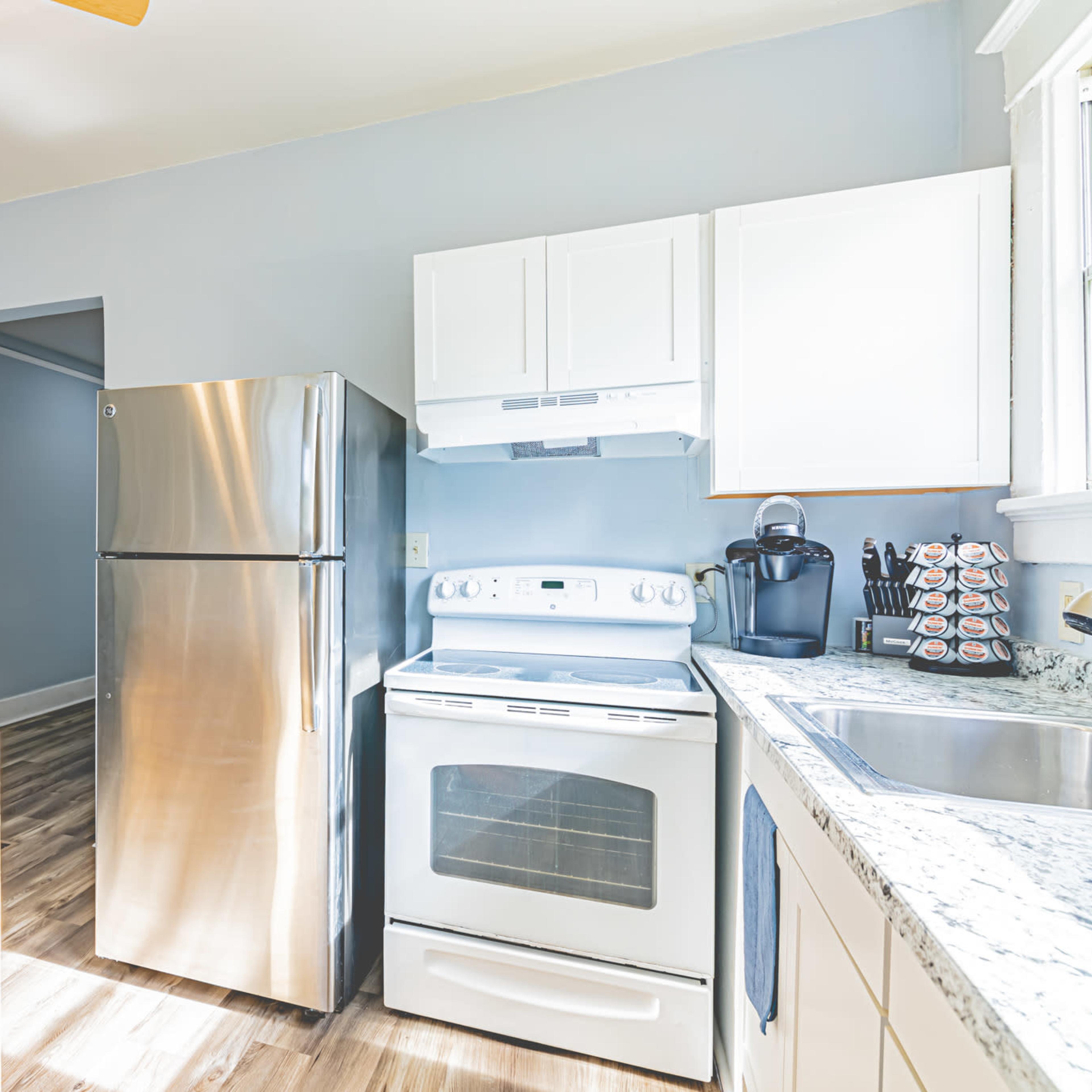 A kitchen with stainless steel appliances, white cabinets, a wooden island, and light blue walls.