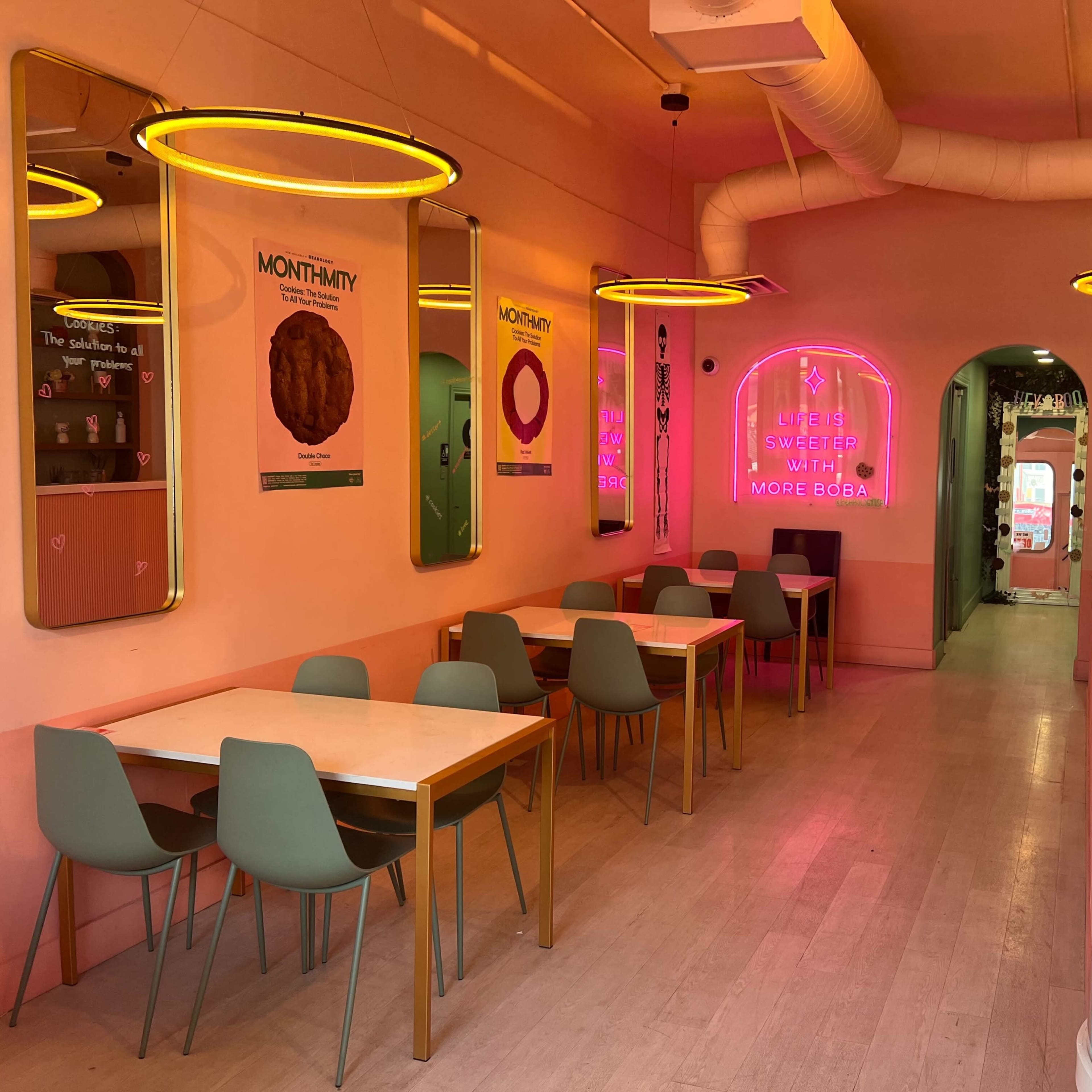A colorful café interior featuring several tables, neon signs, and wall decorations.