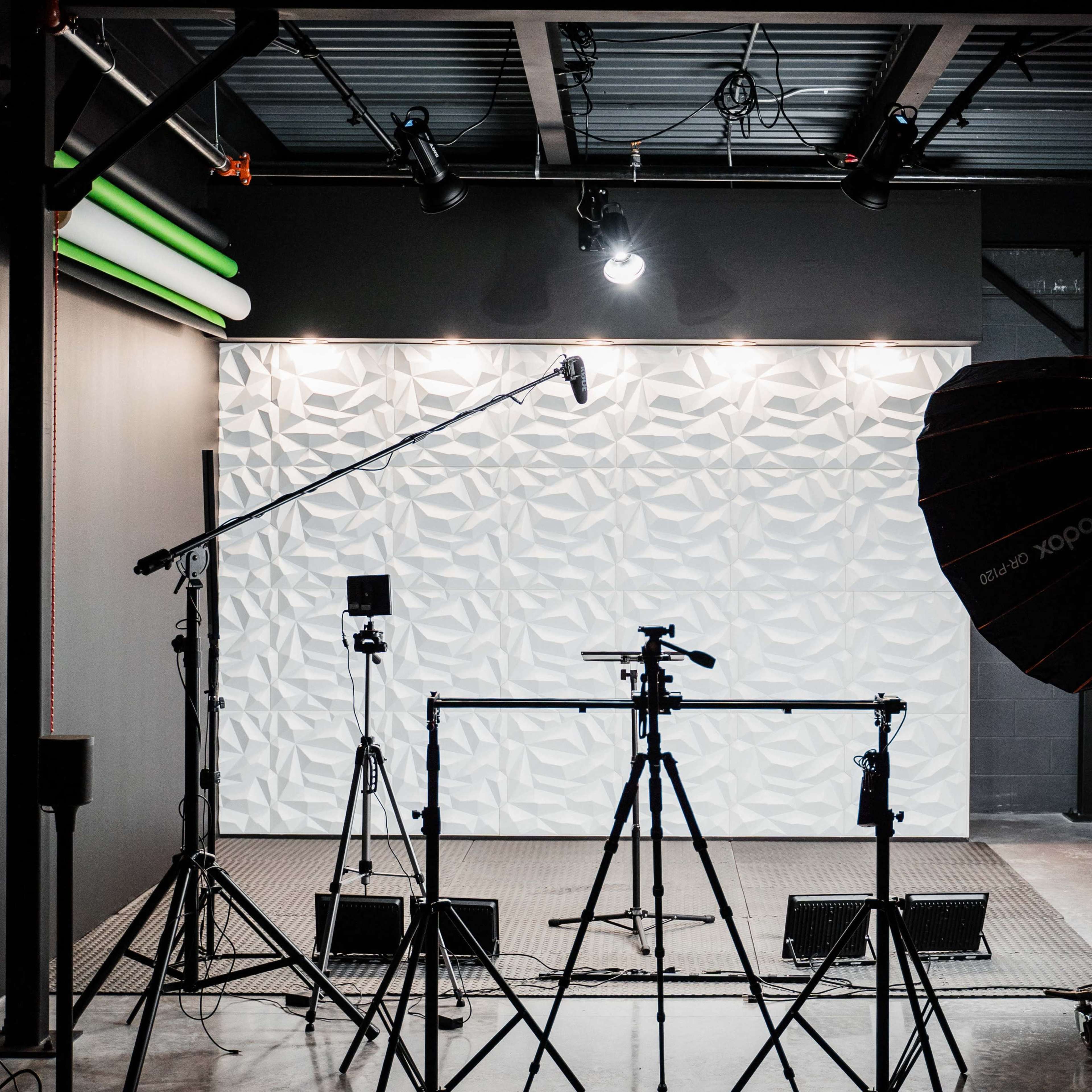 A photography studio is set up with tripods, lighting equipment, and a textured backdrop.