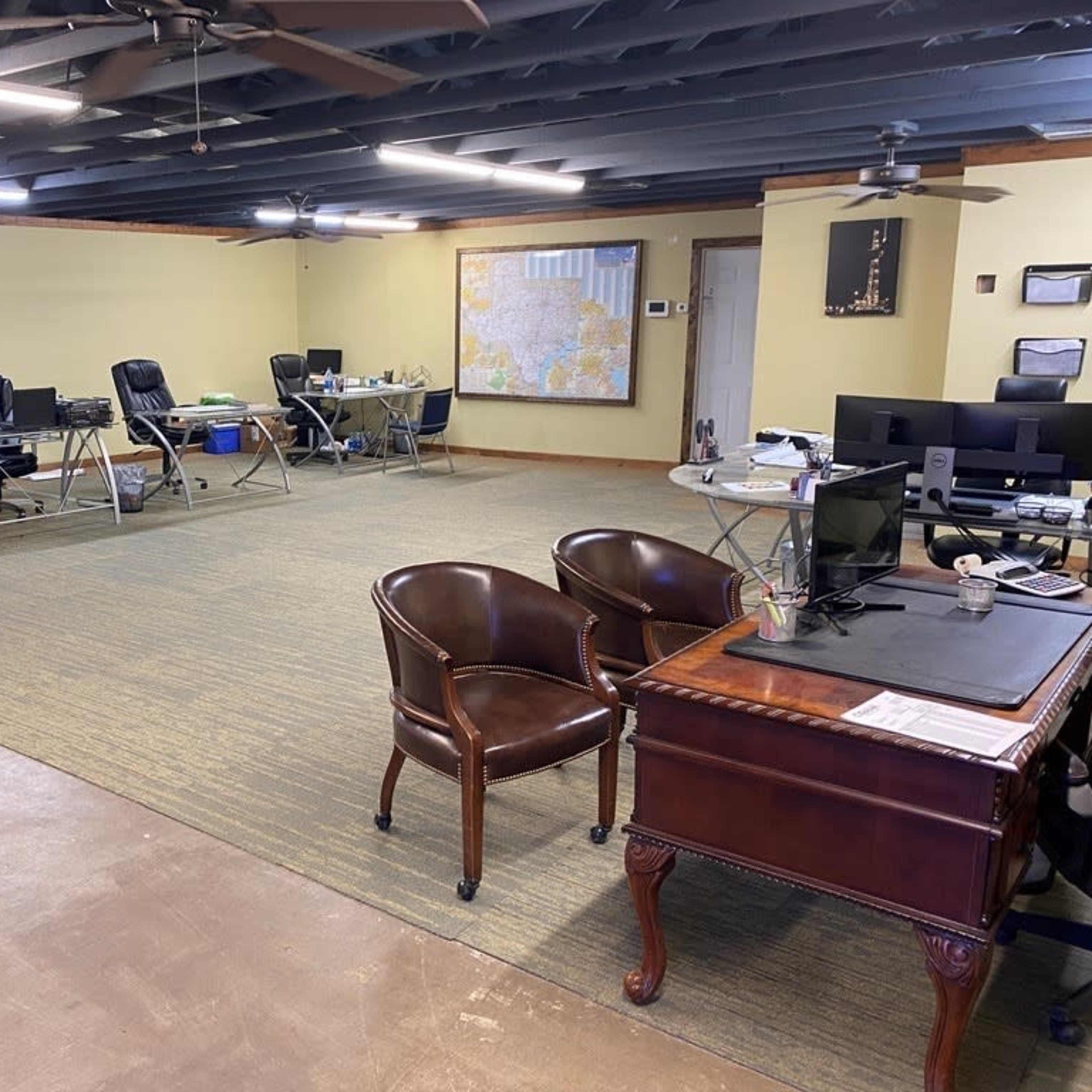 A spacious office space with several desks, chairs, and computers arranged around the room.