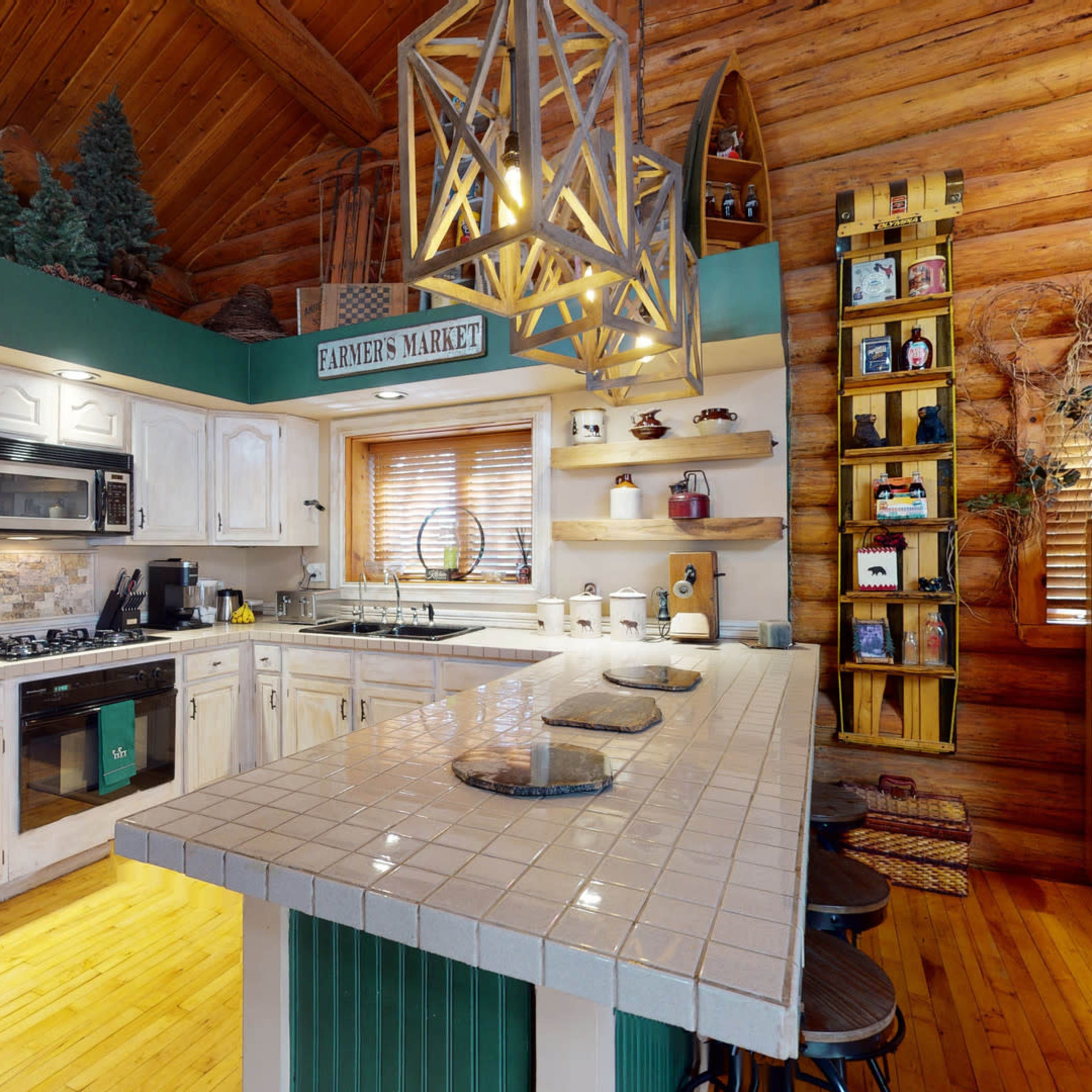 A rustic kitchen with wooden beams, a central island with bar stools, and open shelving displaying various kitchen items.