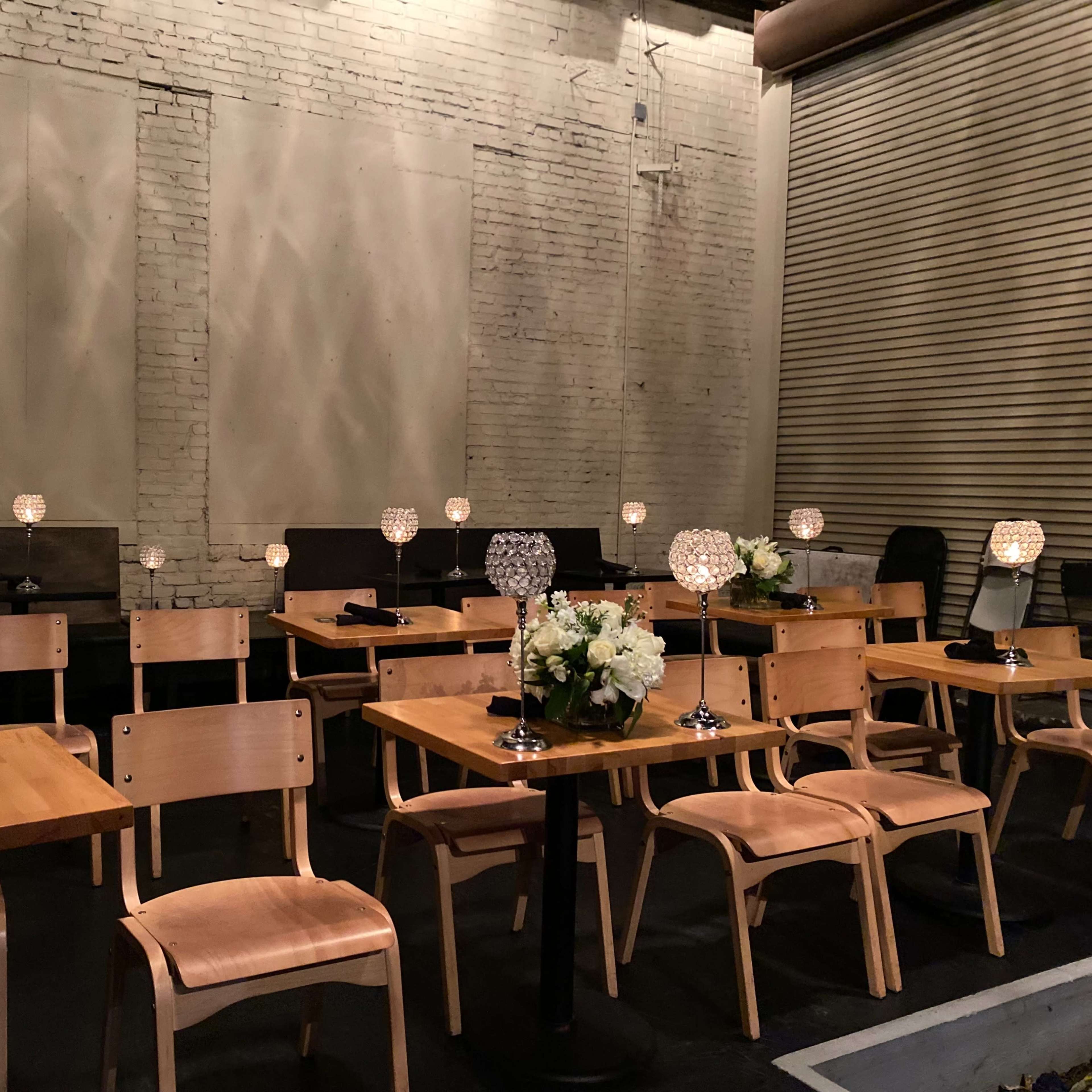A dining area features rows of wooden tables and chairs, each adorned with a decorative lamp and a floral centerpiece.