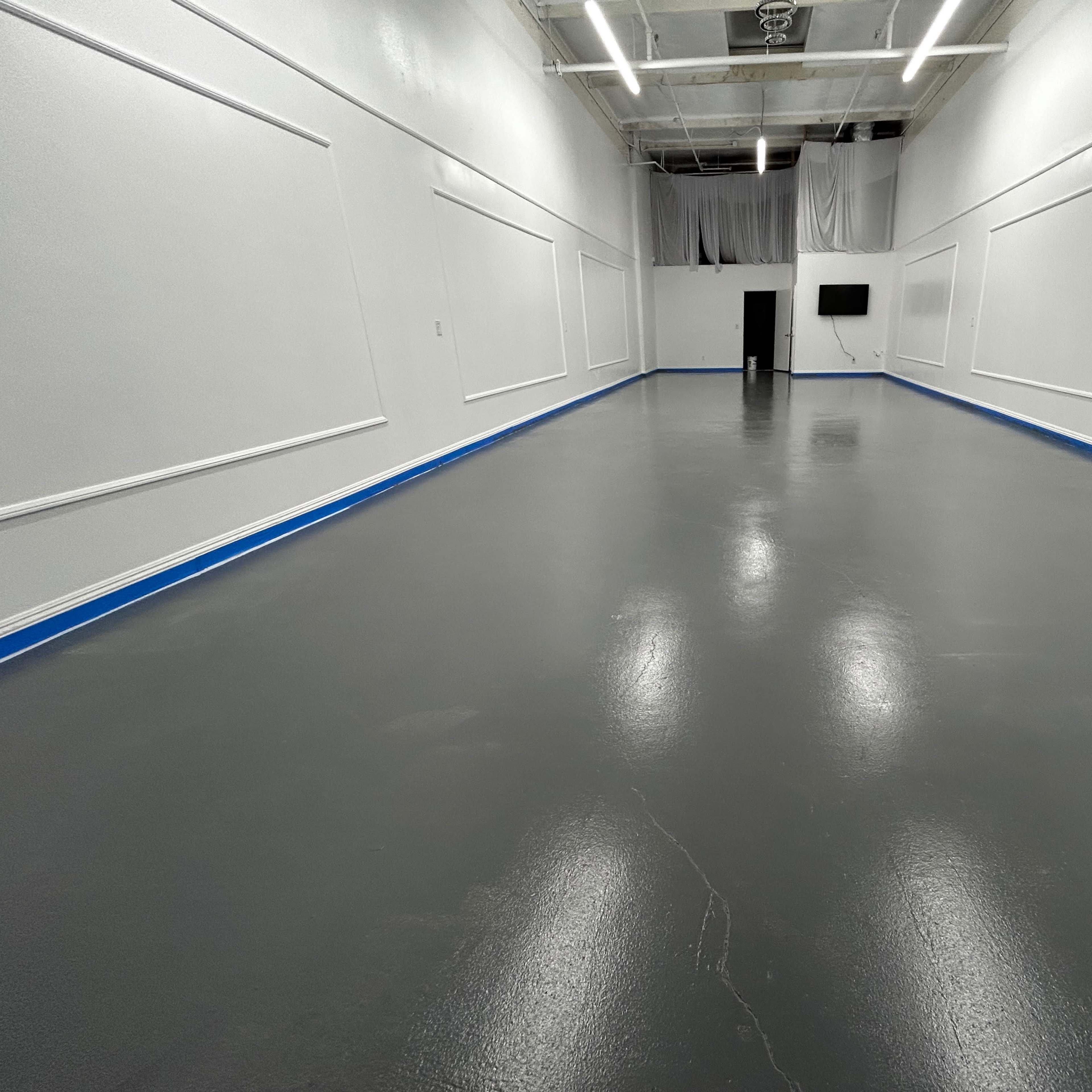 An empty room with a polished gray floor, white walls, and blue trim.