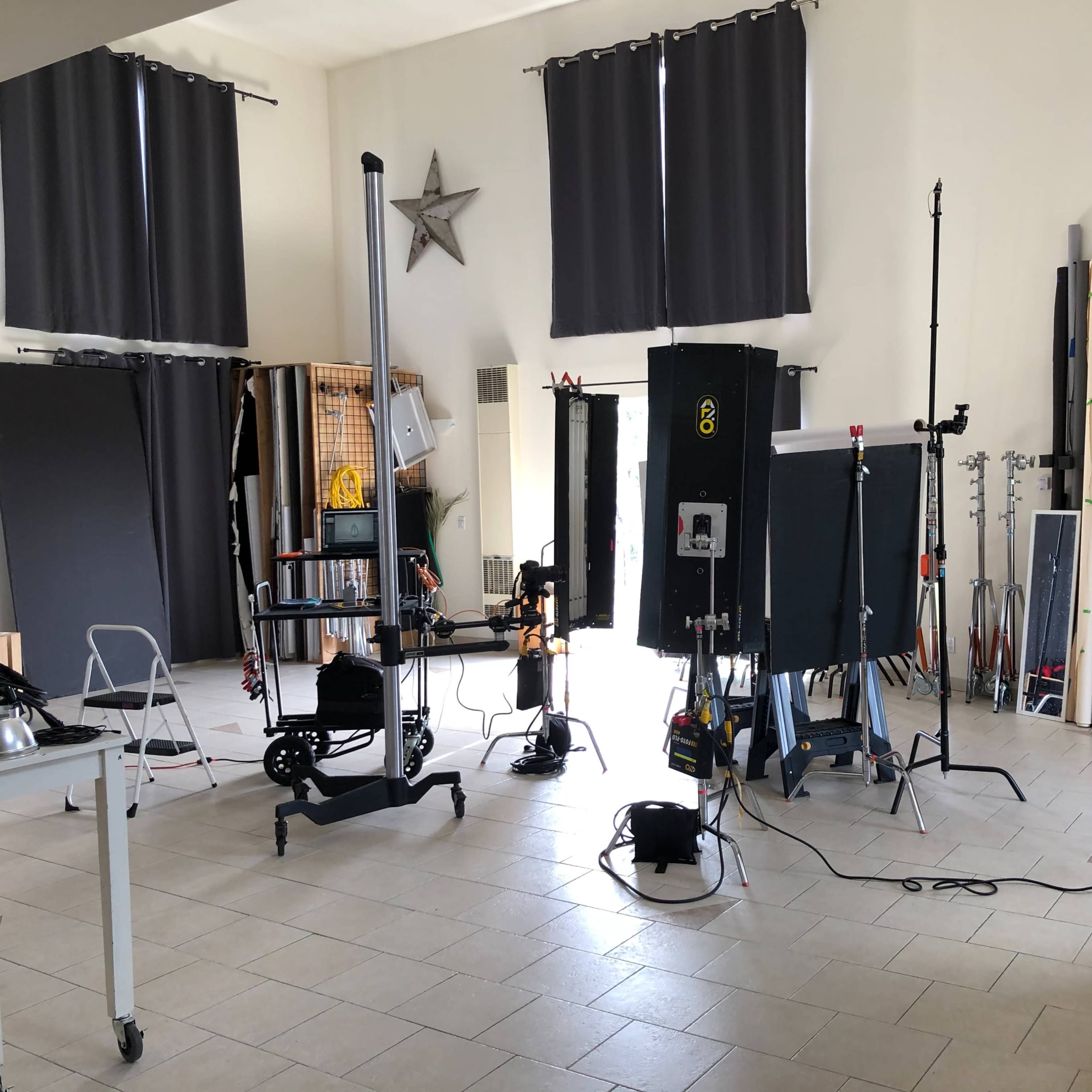 A photography studio equipped with various backdrop rolls, lighting equipment, and props arranged in a spacious area.