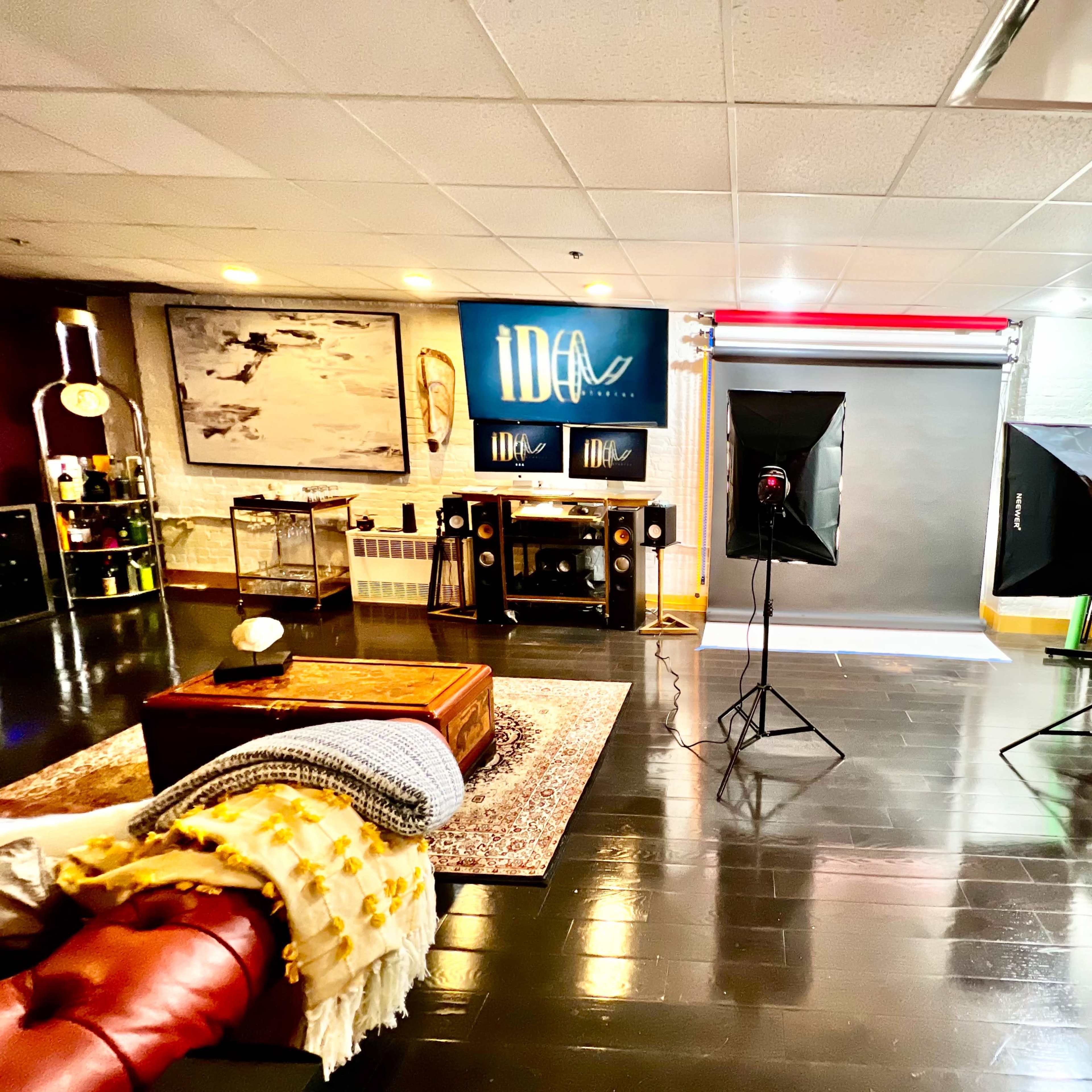 A spacious studio setup with photography equipment, backdrops, and a cozy seating area featuring a couch and decorative accessories.