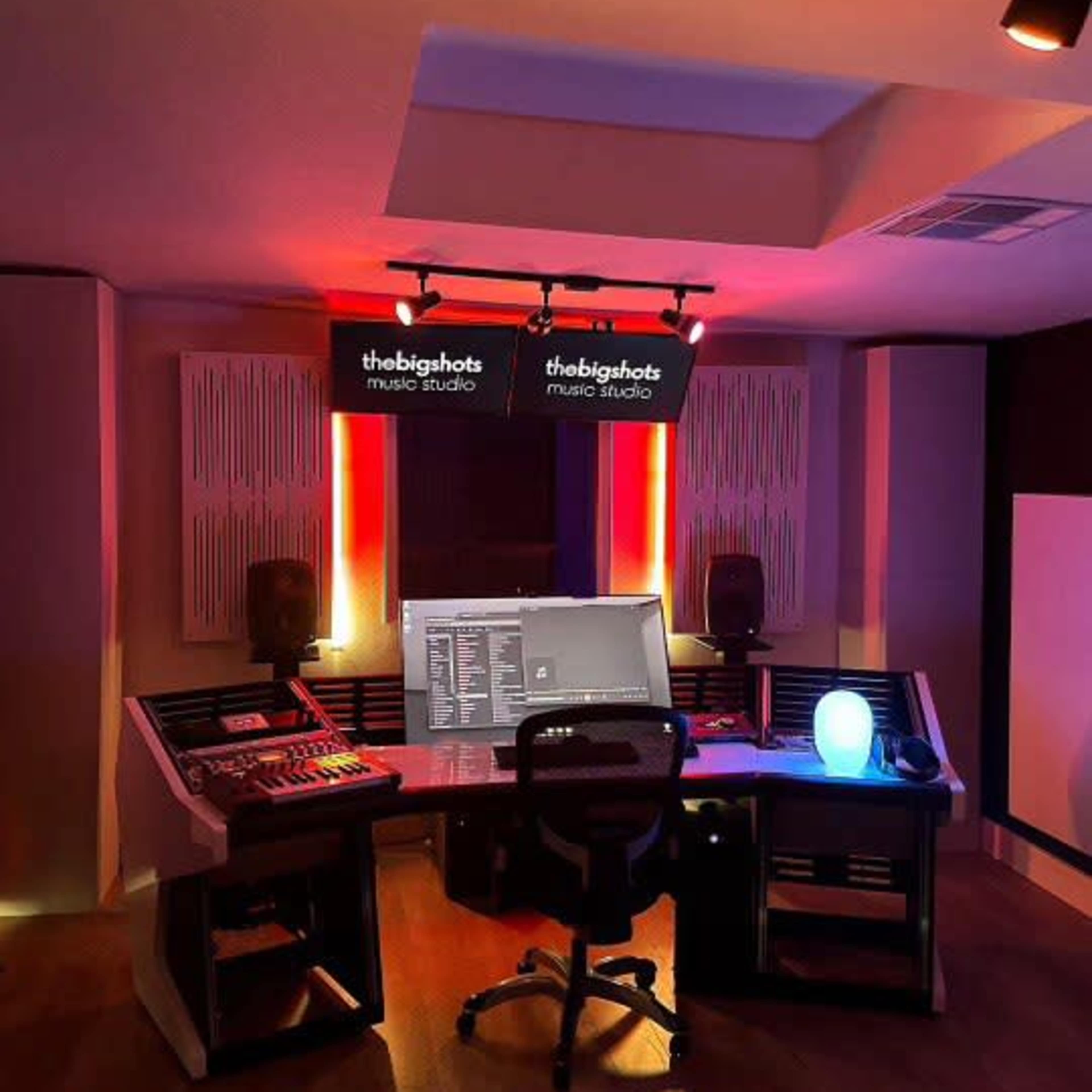 A modern music studio with a control desk, computer monitor, and ambient lighting.