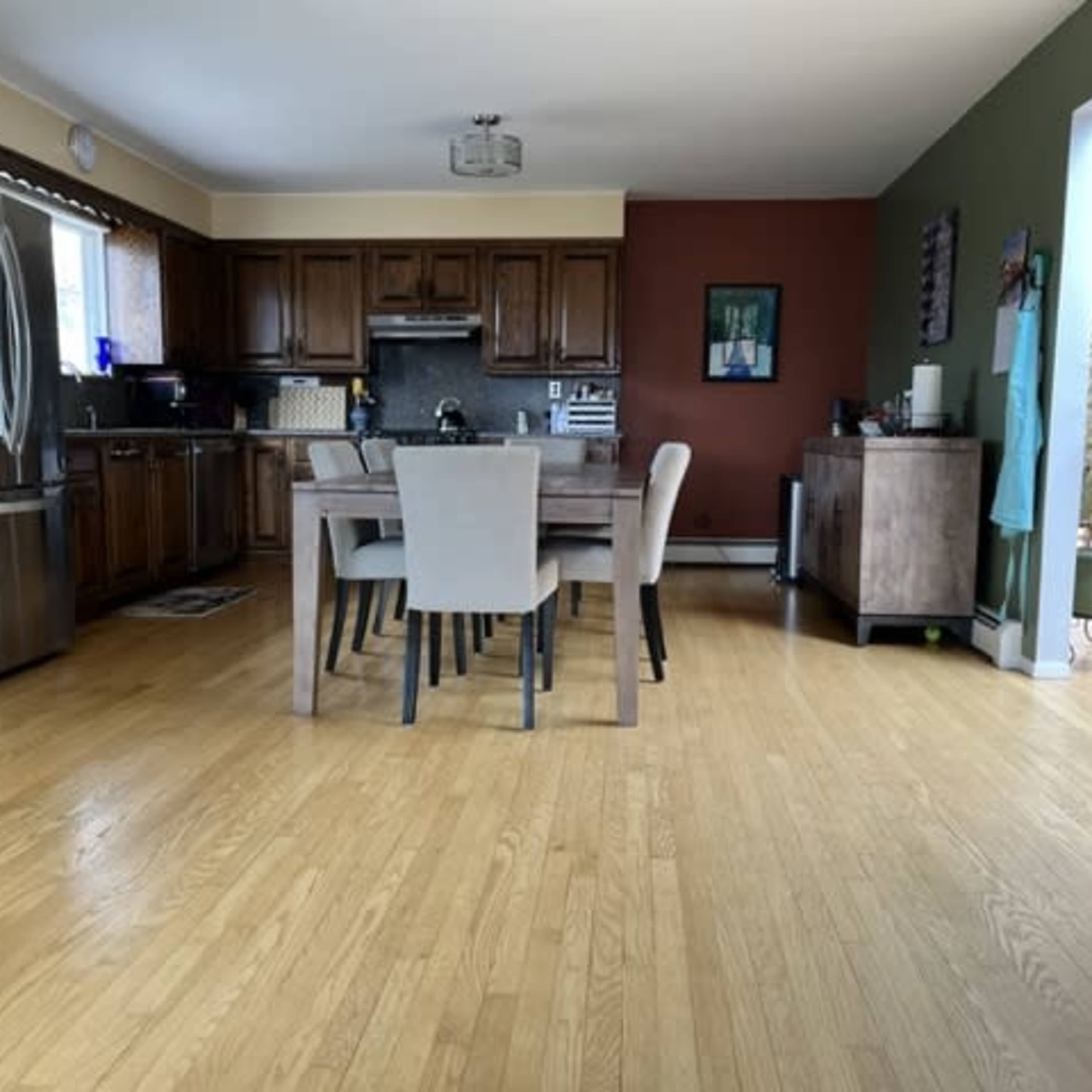 A spacious kitchen features wooden cabinets, a dining table with chairs, and a stainless steel refrigerator.