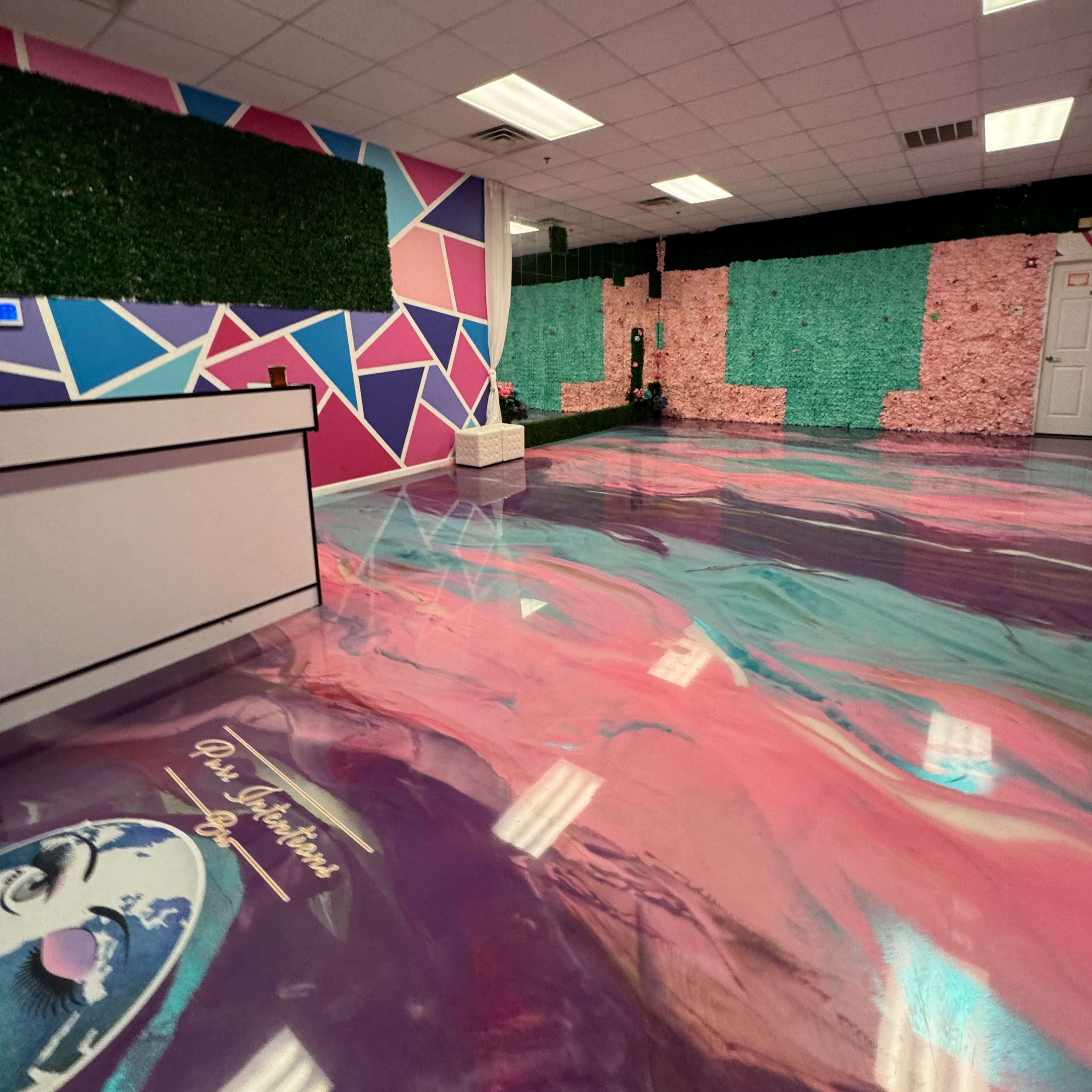 A colorful interior space with geometric wall designs, green foliage accents, and a glossy, patterned floor.