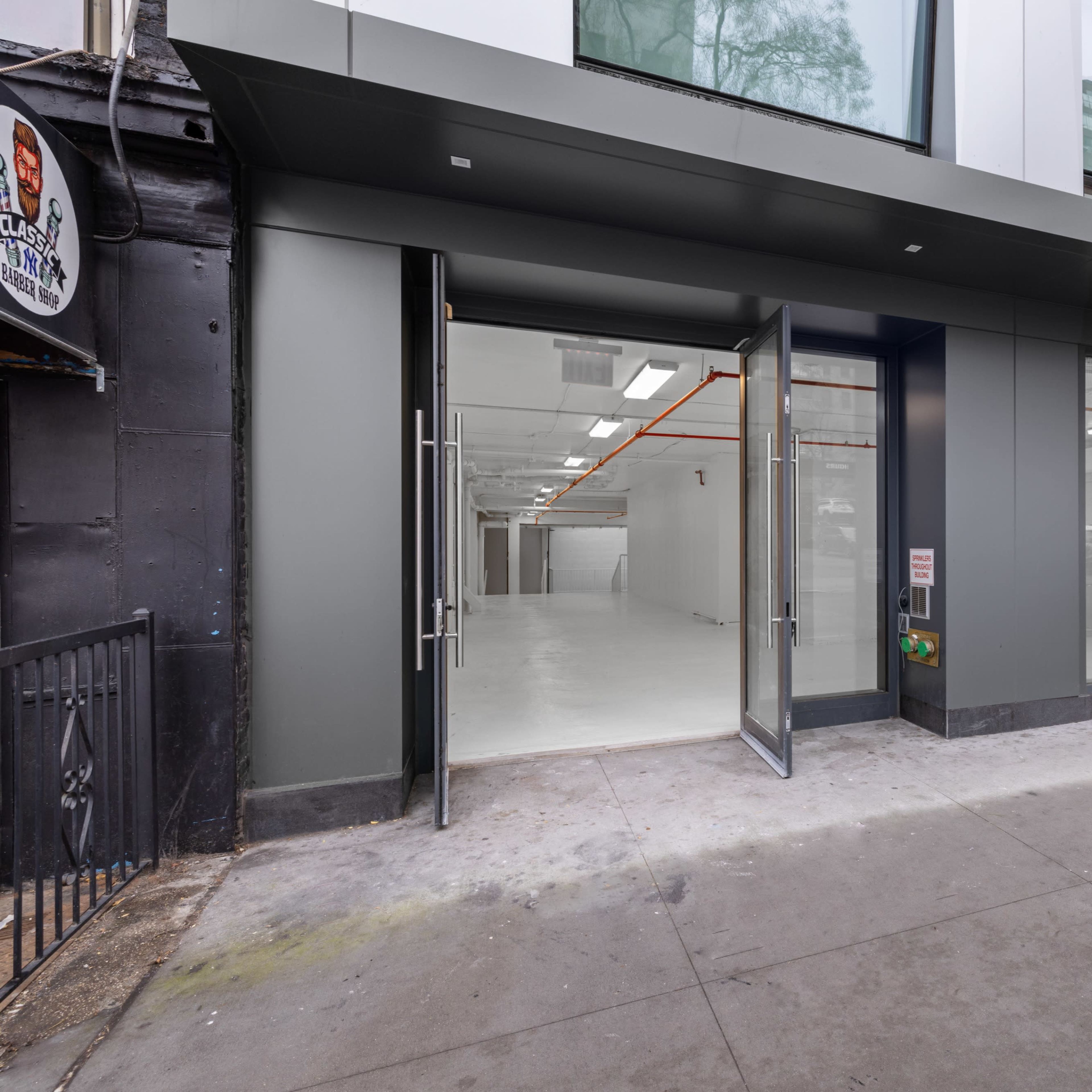 A modern commercial building entrance with glass doors leading to an empty interior space.