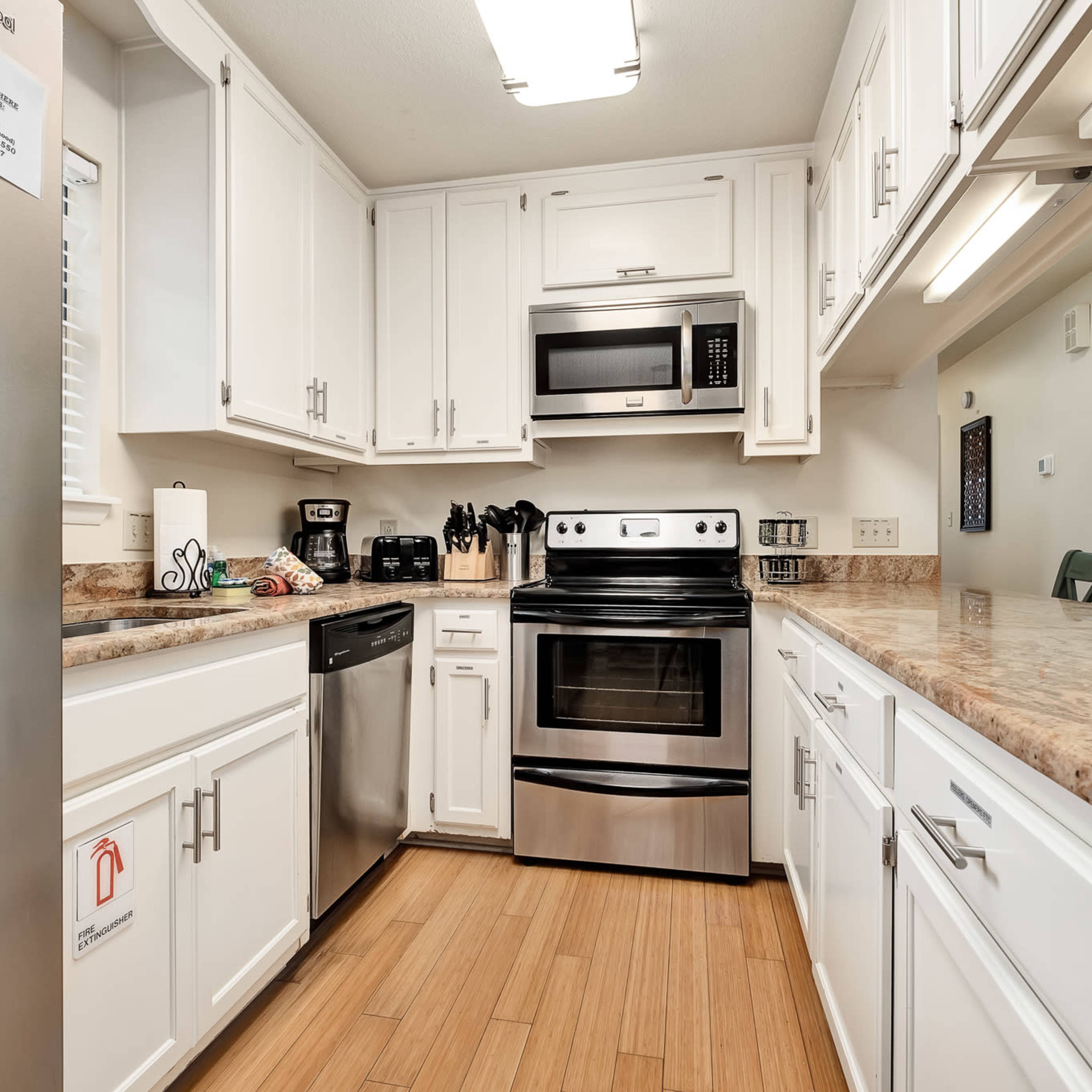 A modern kitchen featuring white cabinets, stainless steel appliances, and a countertop made of light-colored stone.