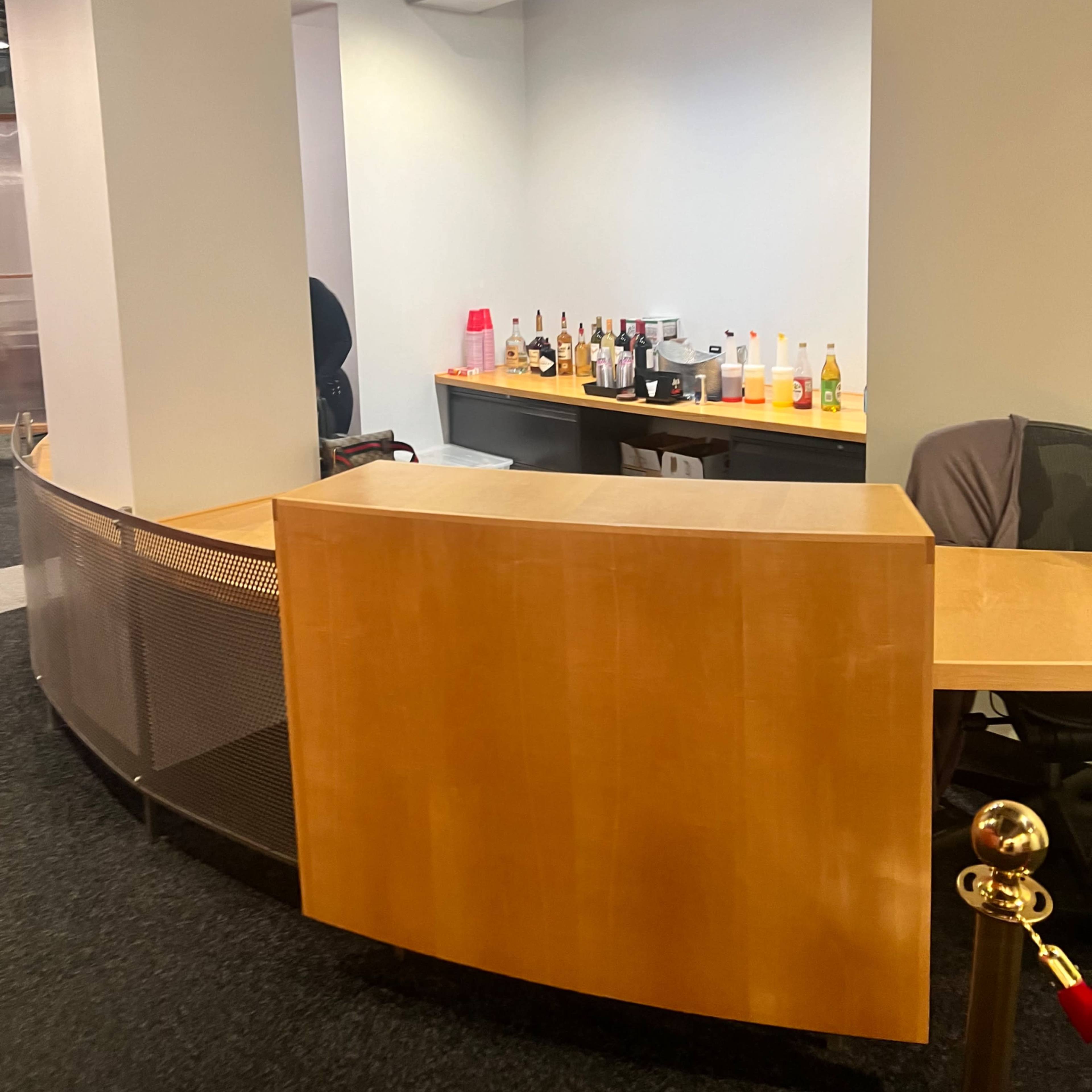 A wooden reception desk with a variety of bottles displayed on a countertop in an office setting.