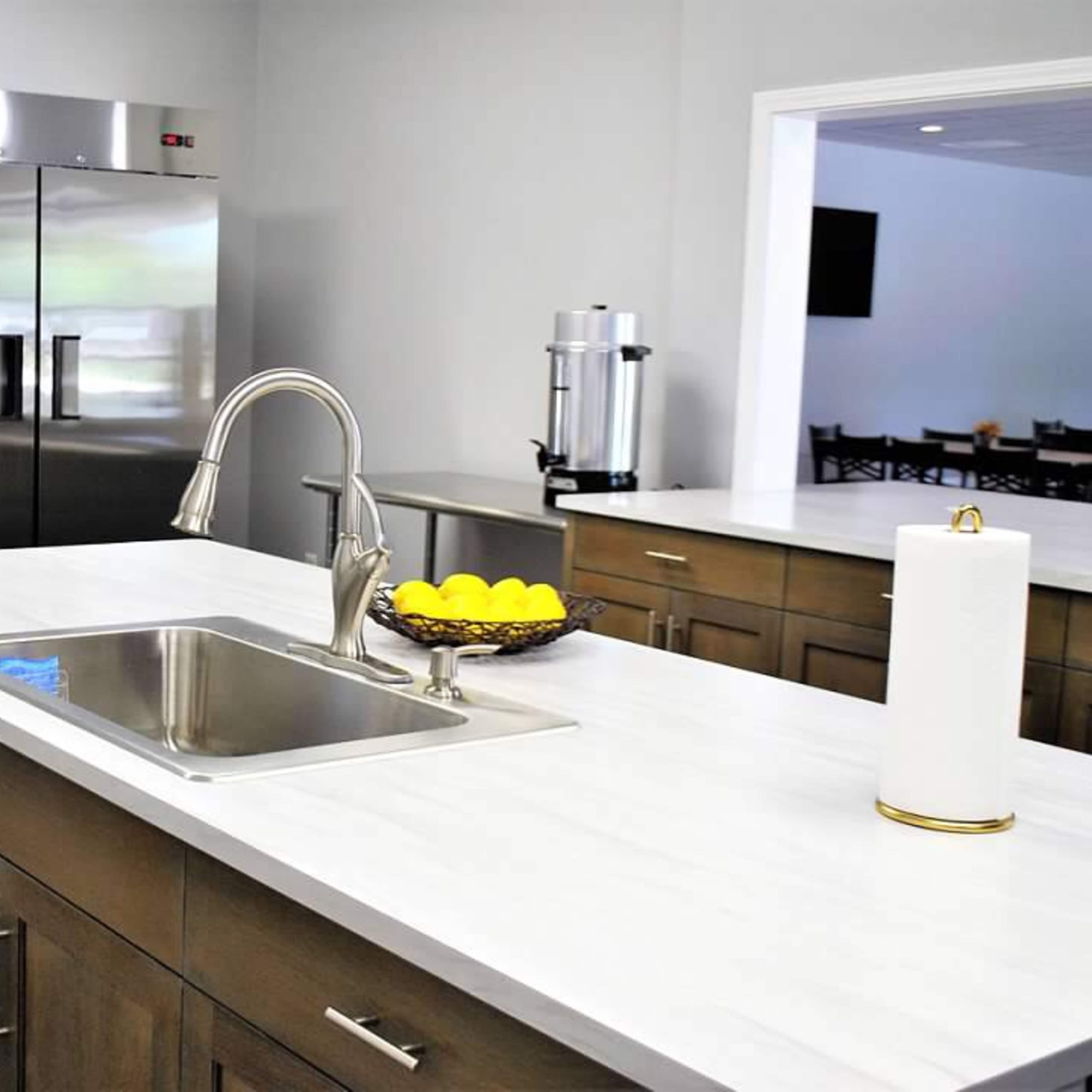 A modern kitchen with stainless steel refrigerators, a sink on a countertop, and a bowl of lemons.