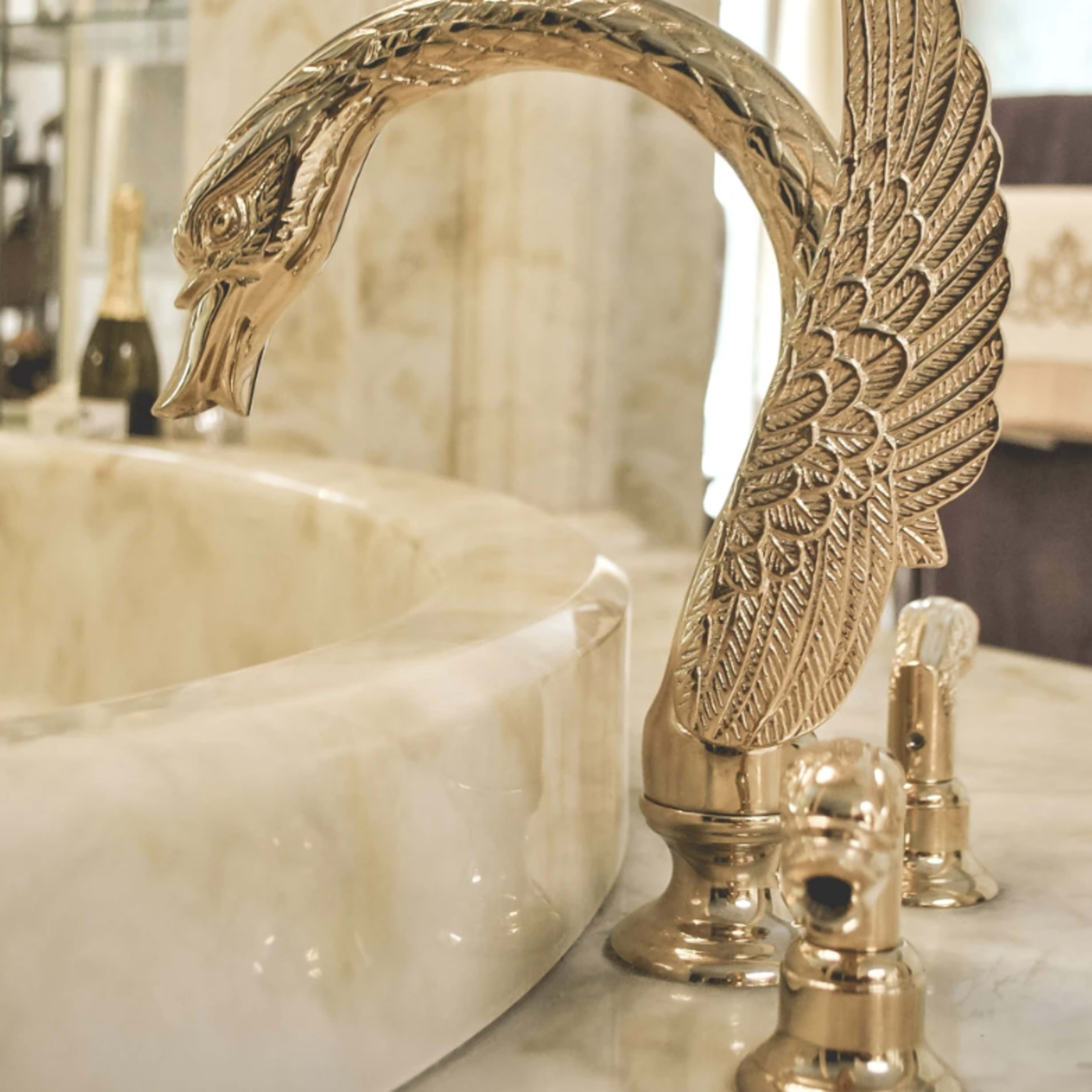A decorative faucet shaped like a swan's neck is installed on a marble countertop next to two knobs.