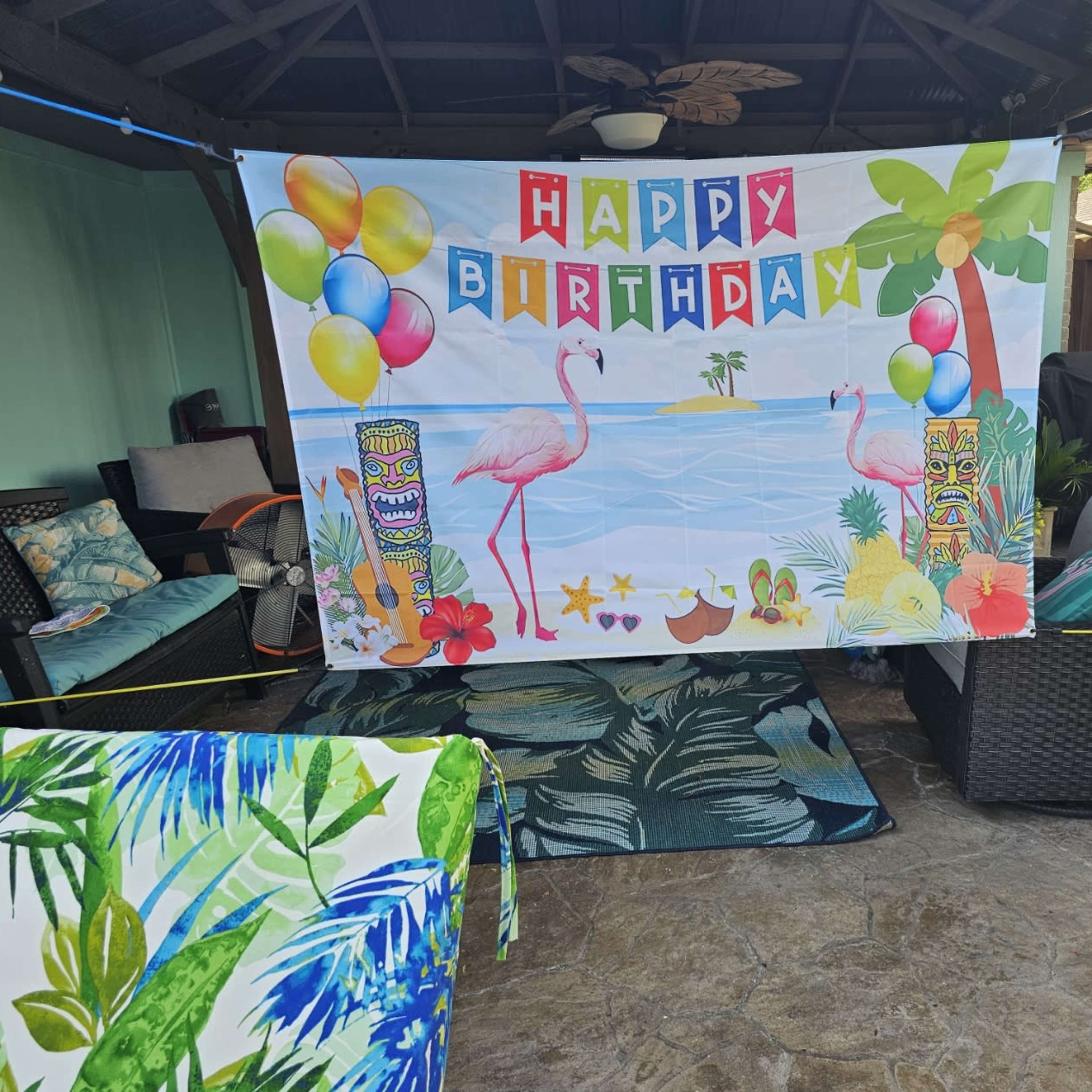 A decorated patio area with a large "Happy Birthday" banner featuring flamingos and tropical elements.