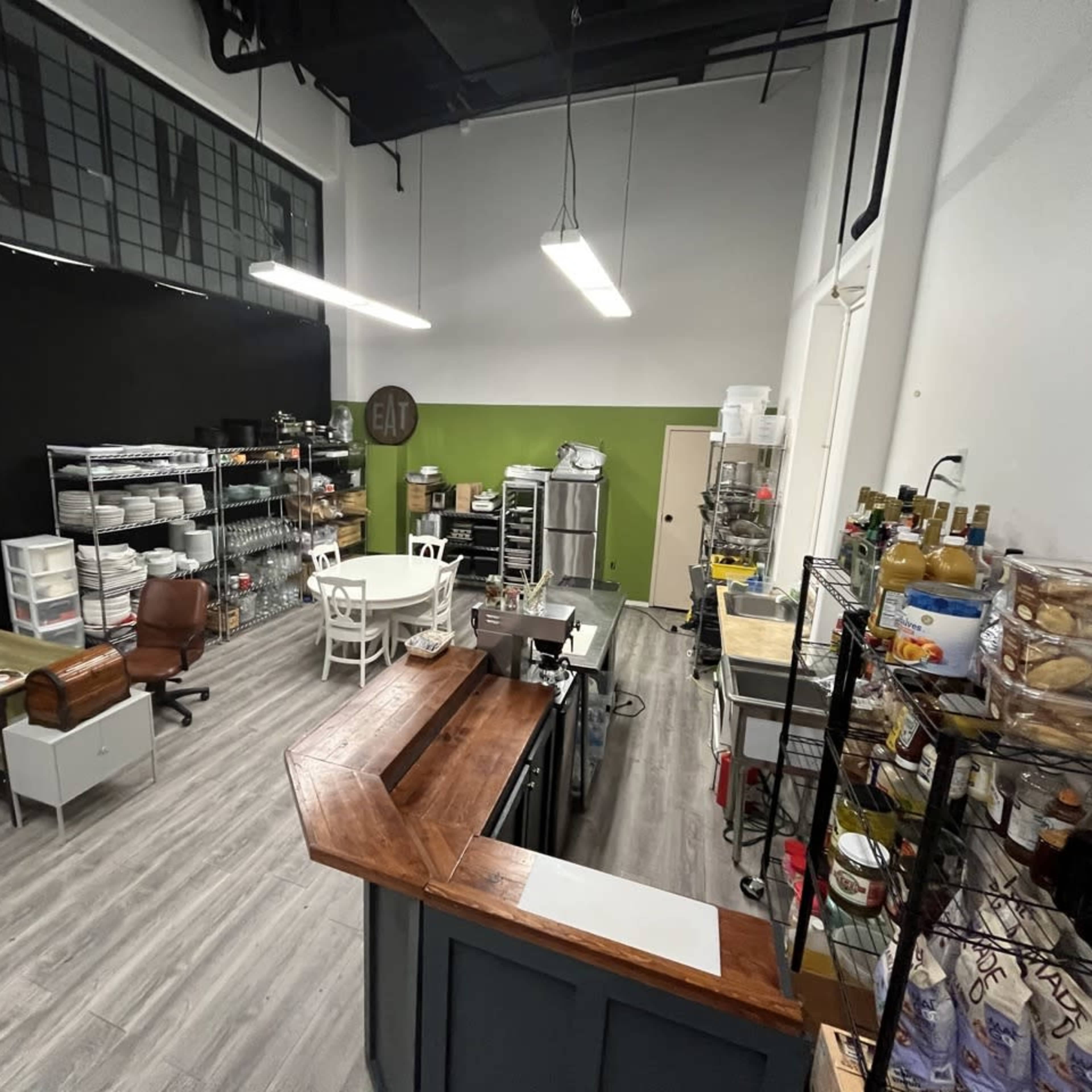 A spacious commercial kitchen with various storage units, a central table, and a large preparation counter.