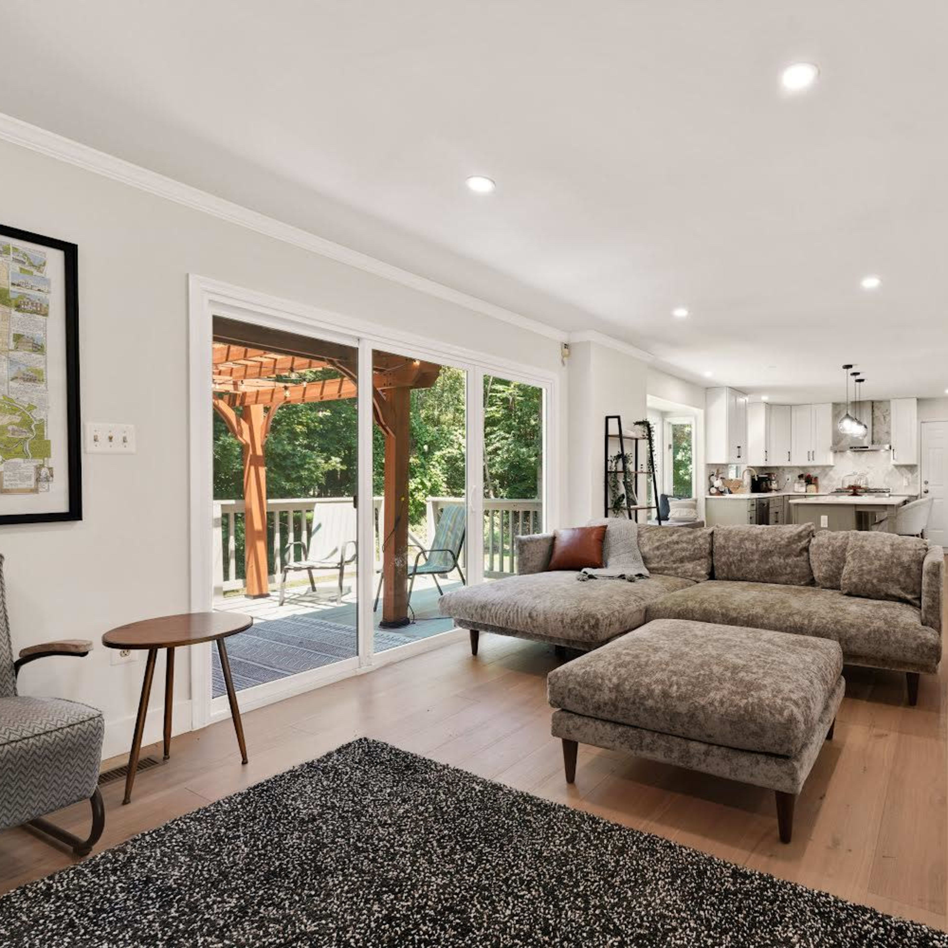 A spacious living room with a large sectional sofa, a coffee table, and sliding glass doors leading to an outdoor deck area.