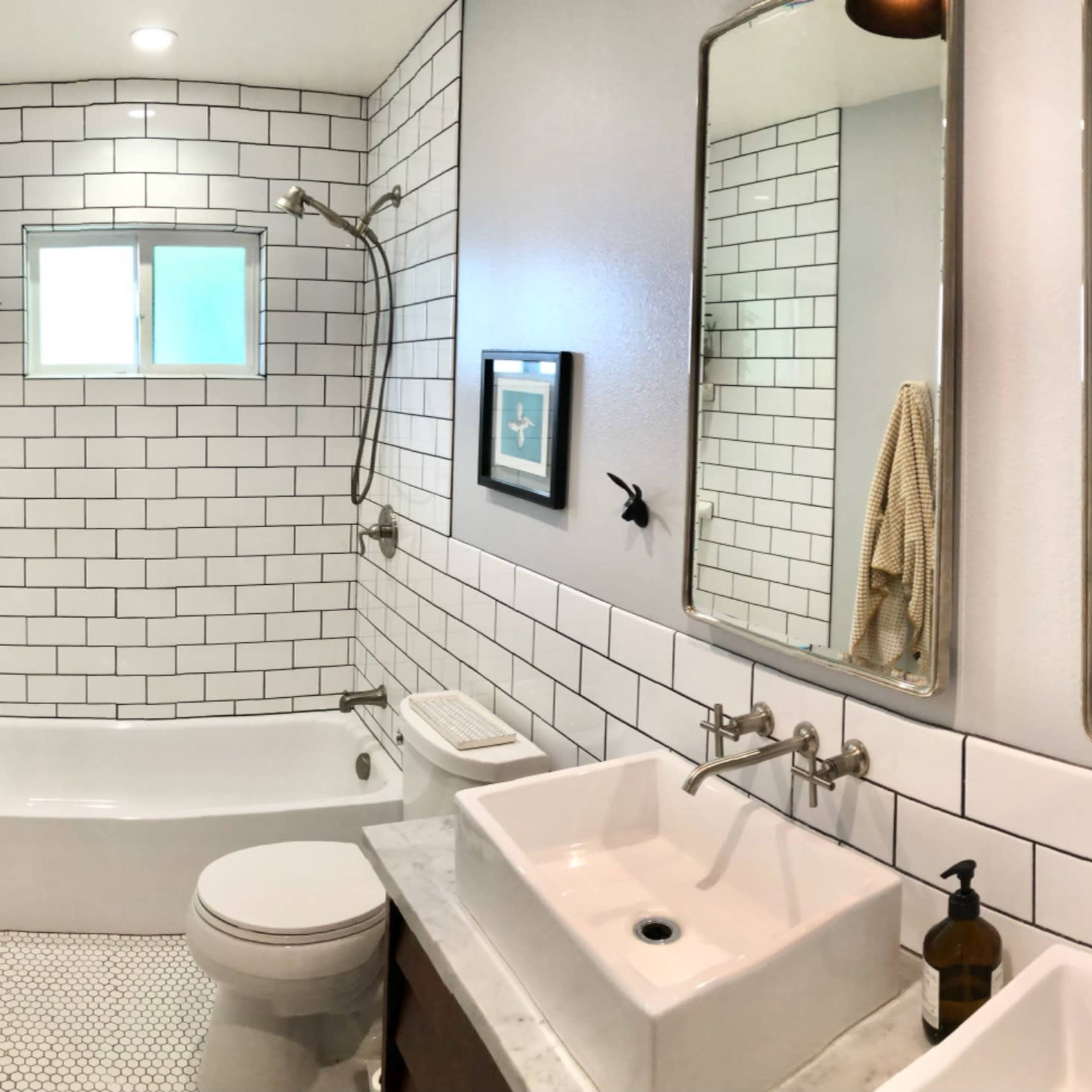 A modern bathroom featuring a white tiled shower area, two sinks with wall-mounted faucets, and a large mirror above each sink.