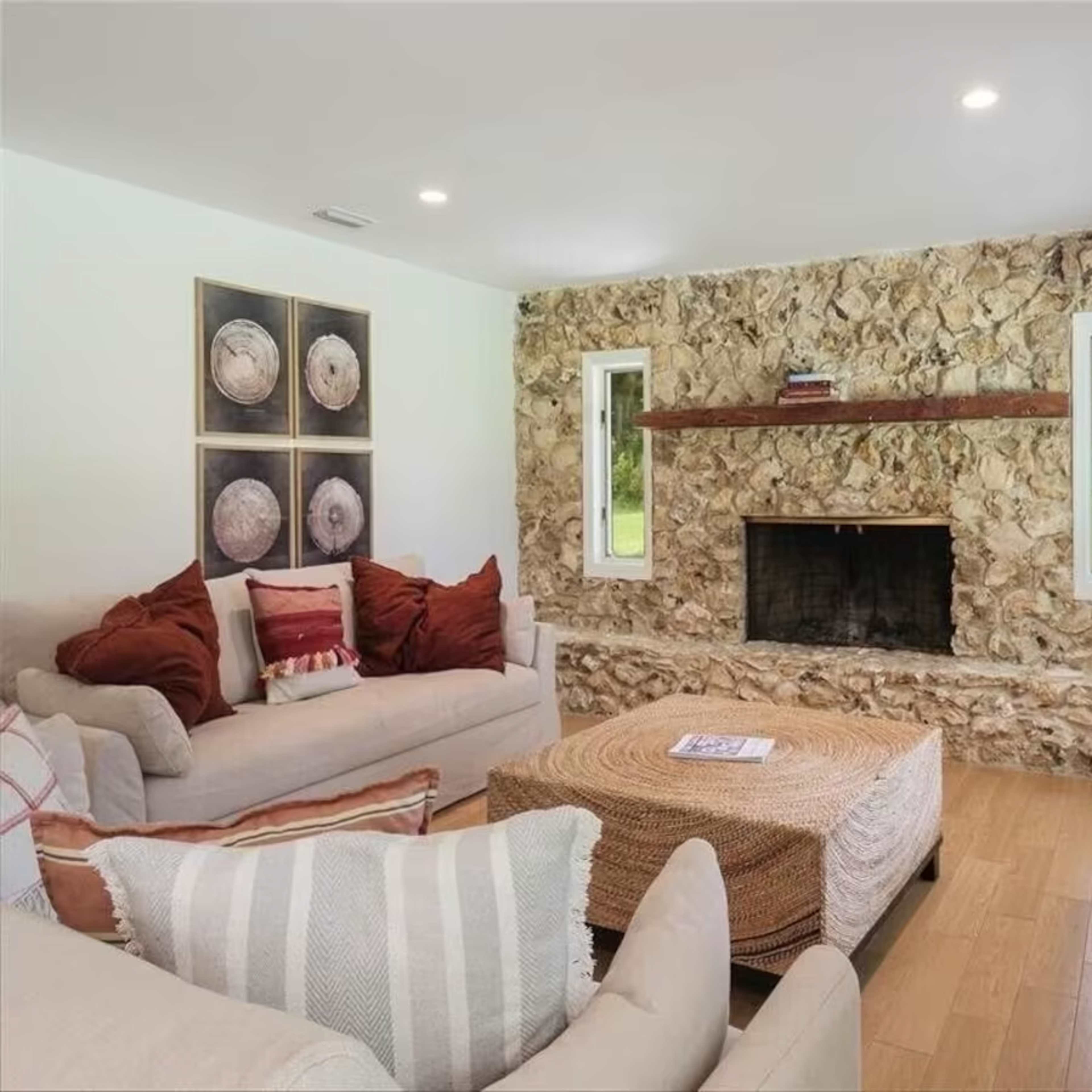 The living room features a stone accent wall with a fireplace, surrounded by light-colored sofas and decorative pillows.