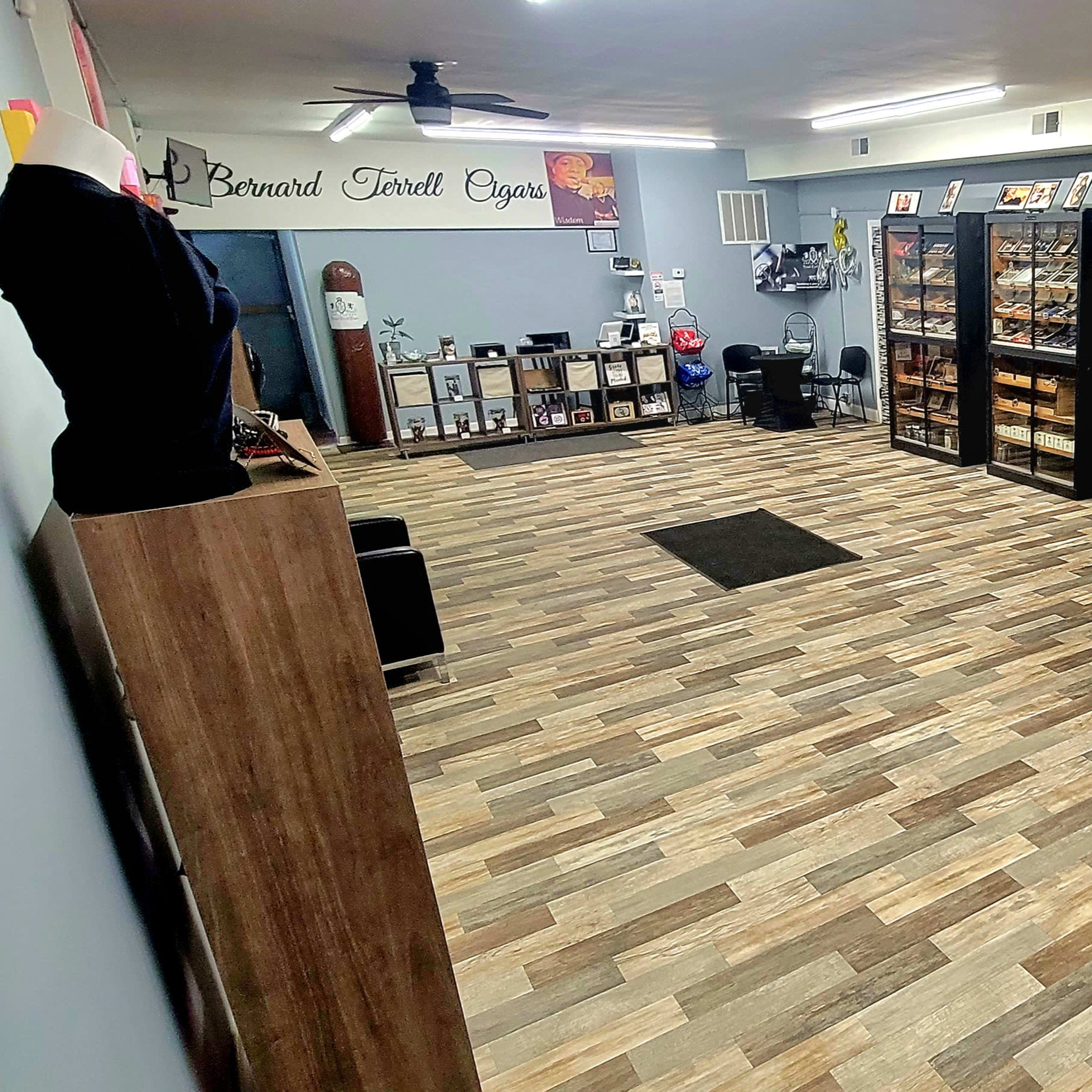 A spacious room with wooden flooring, displaying shelves filled with various items and a few tables and chairs arranged in the space.