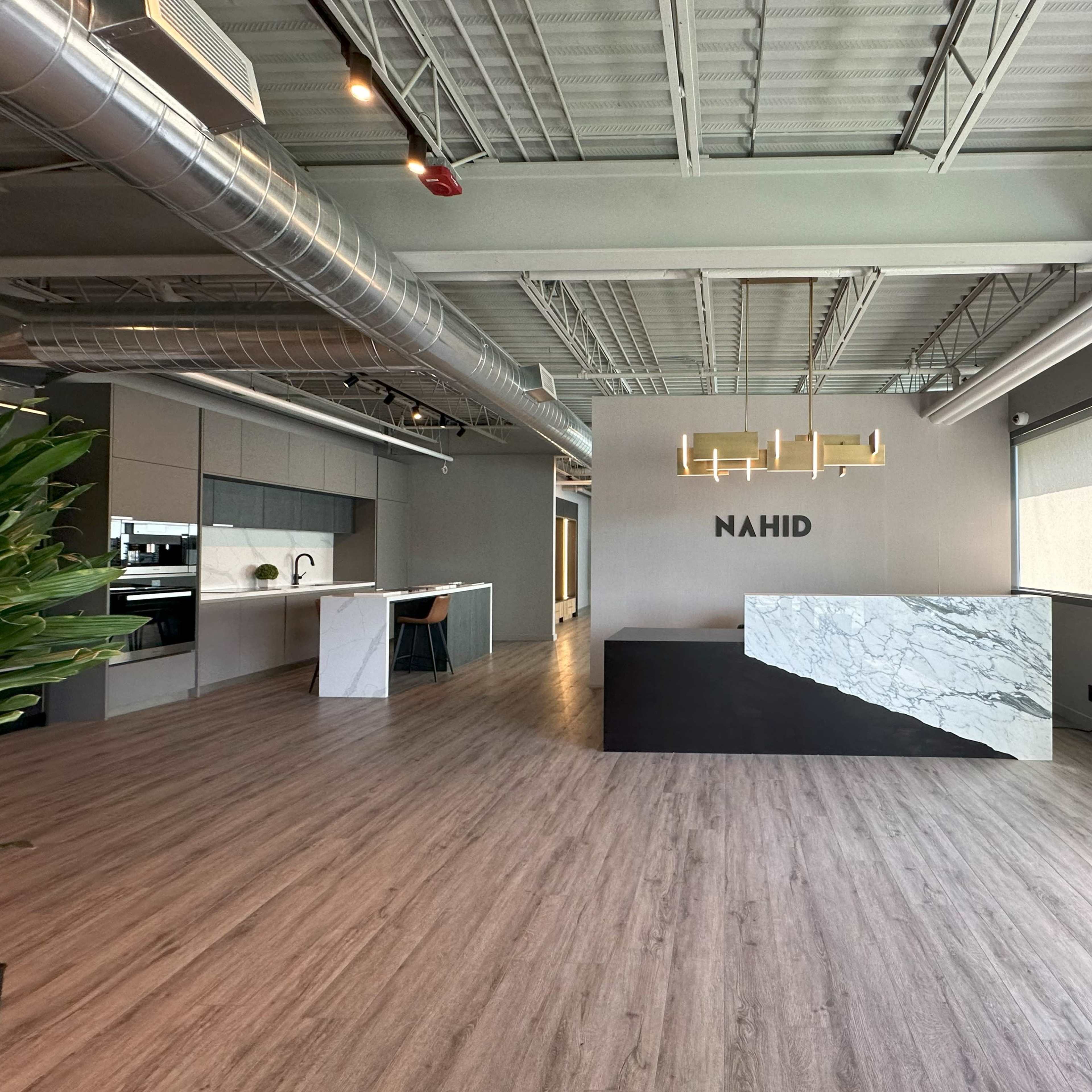 A modern office reception area with a marble front desk and the name "NAHID" displayed on the wall in a minimalist design.