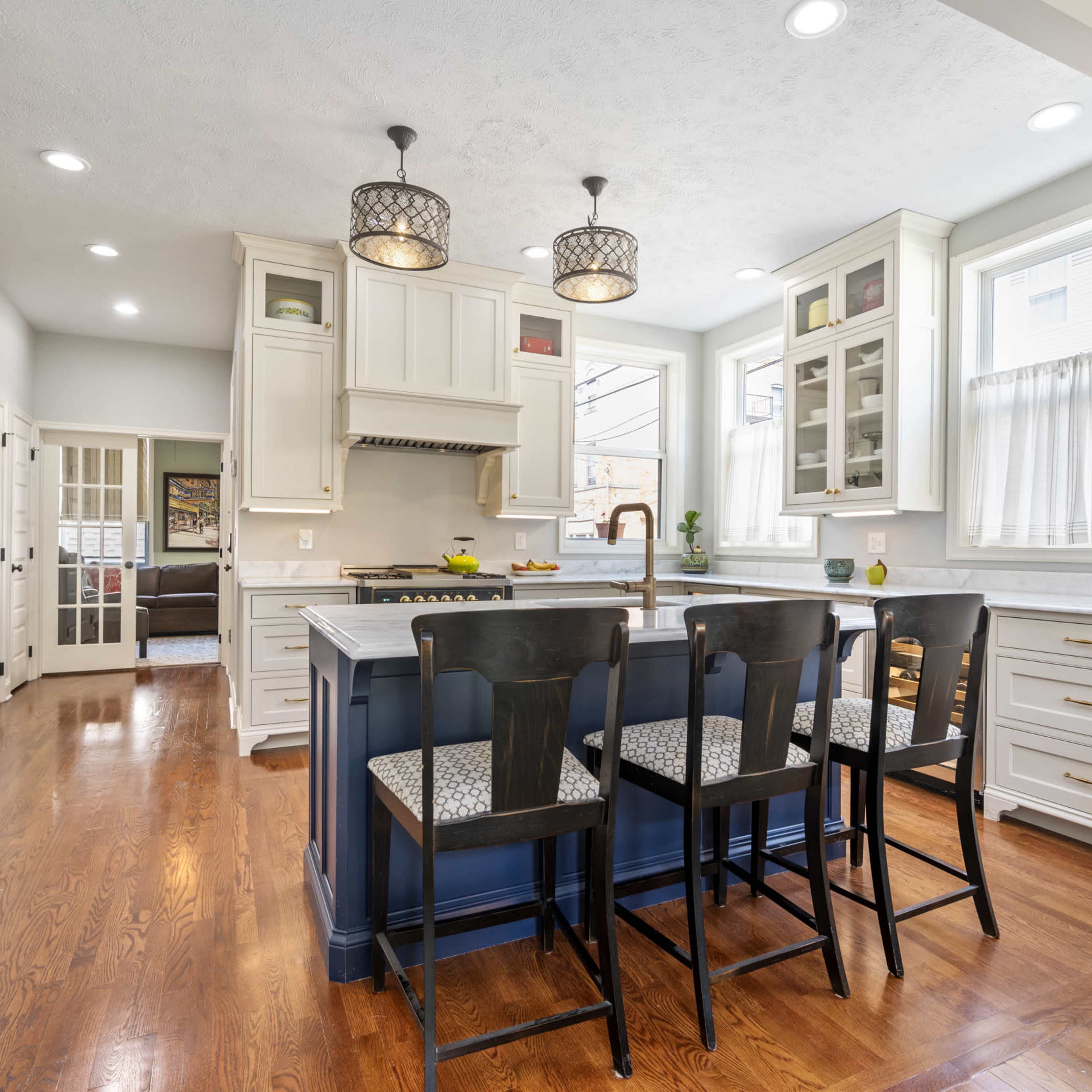 A modern kitchen featuring a central island with seating, white cabinetry, and pendant lighting.
