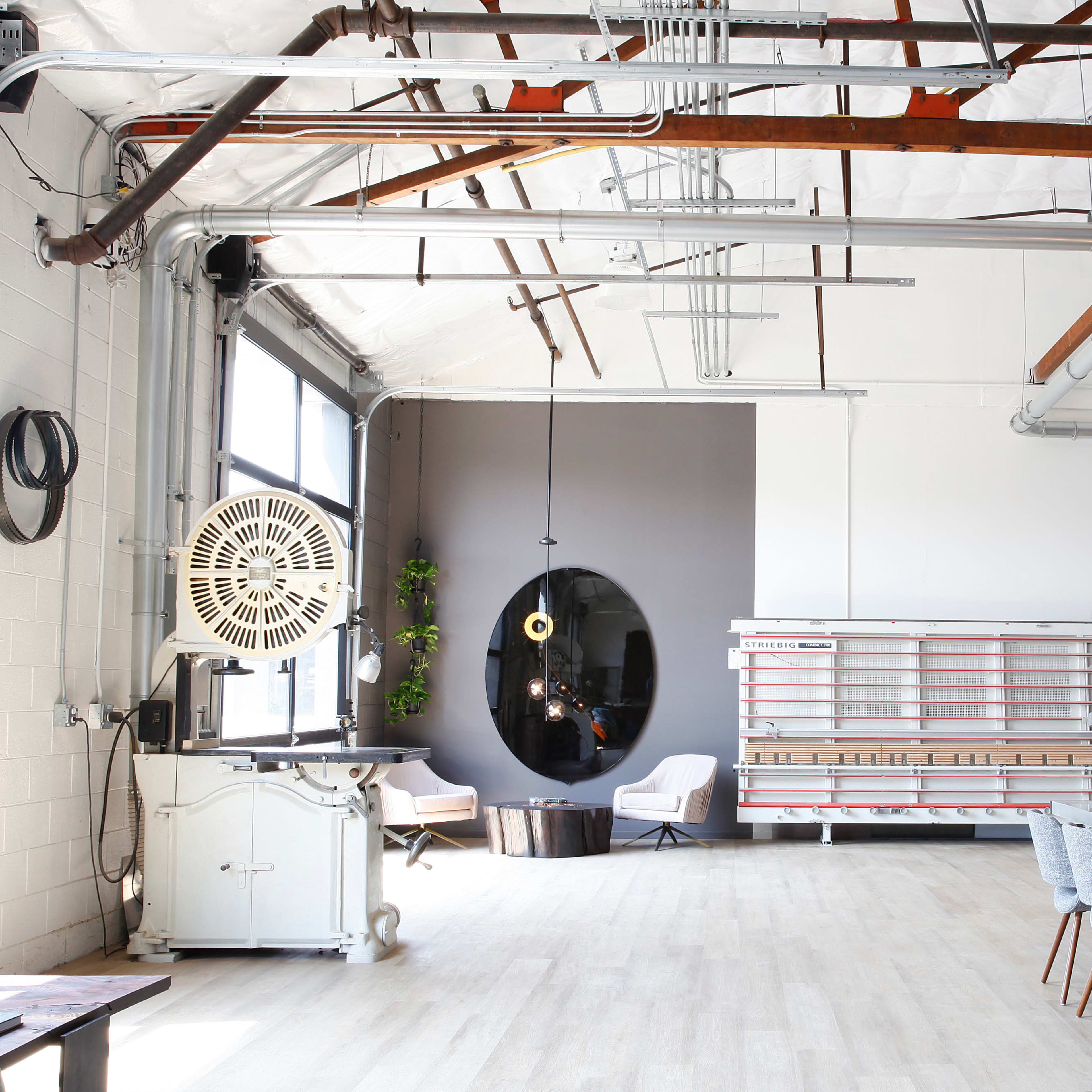 A spacious industrial-style interior with high ceilings, large windows, a mix of seating areas, and a long dining table.