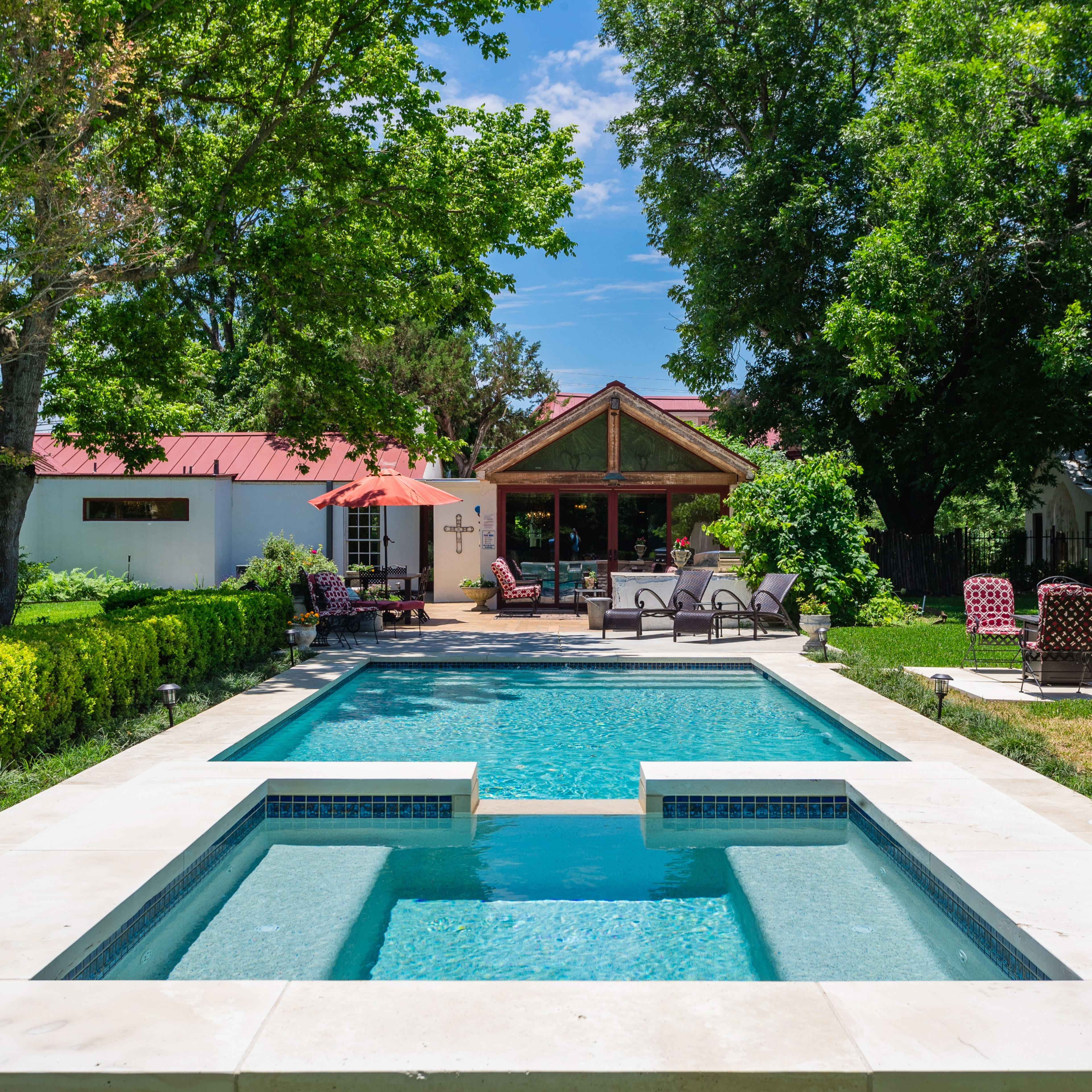 A backyard with a swimming pool surrounded by a landscaped garden and outdoor seating areas.