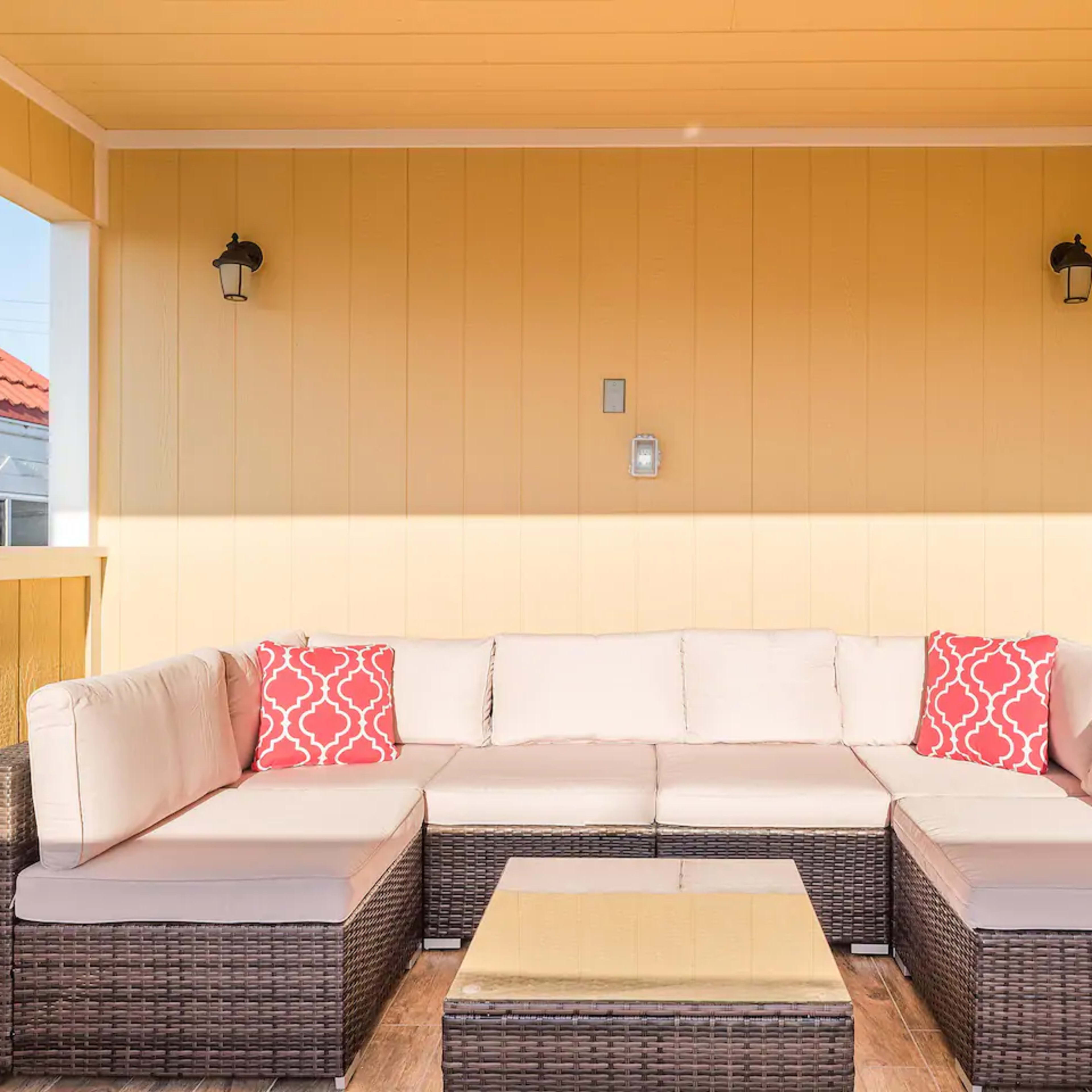 A modern seating area with a light-colored sectional sofa and a square coffee table is set against a yellow wall.