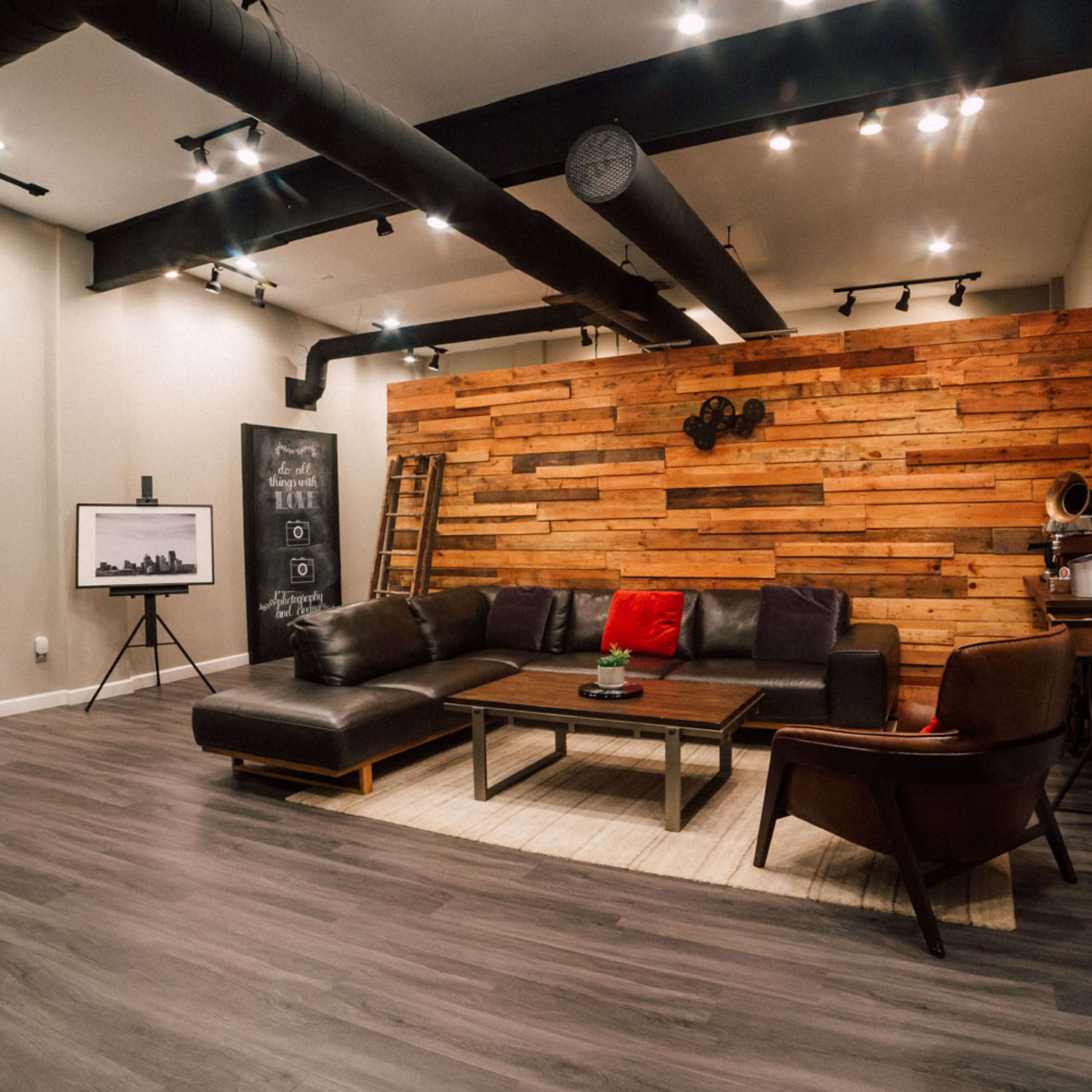 A modern living room featuring a leather sectional couch, a wooden wall with decorative elements, and a large television on a stand.