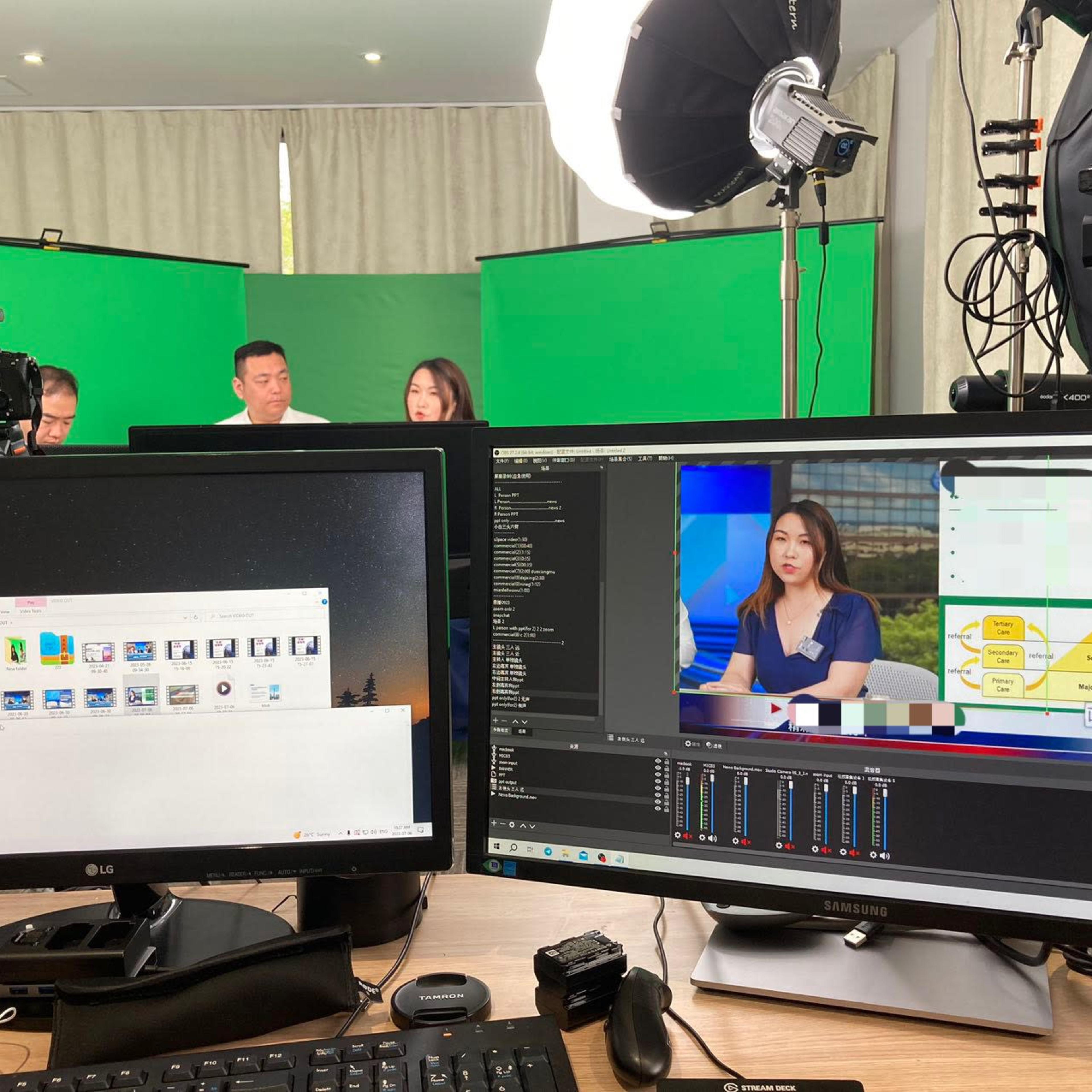 A video production setup with multiple cameras, green screens, and computer monitors displaying a live broadcast featuring a presenter.