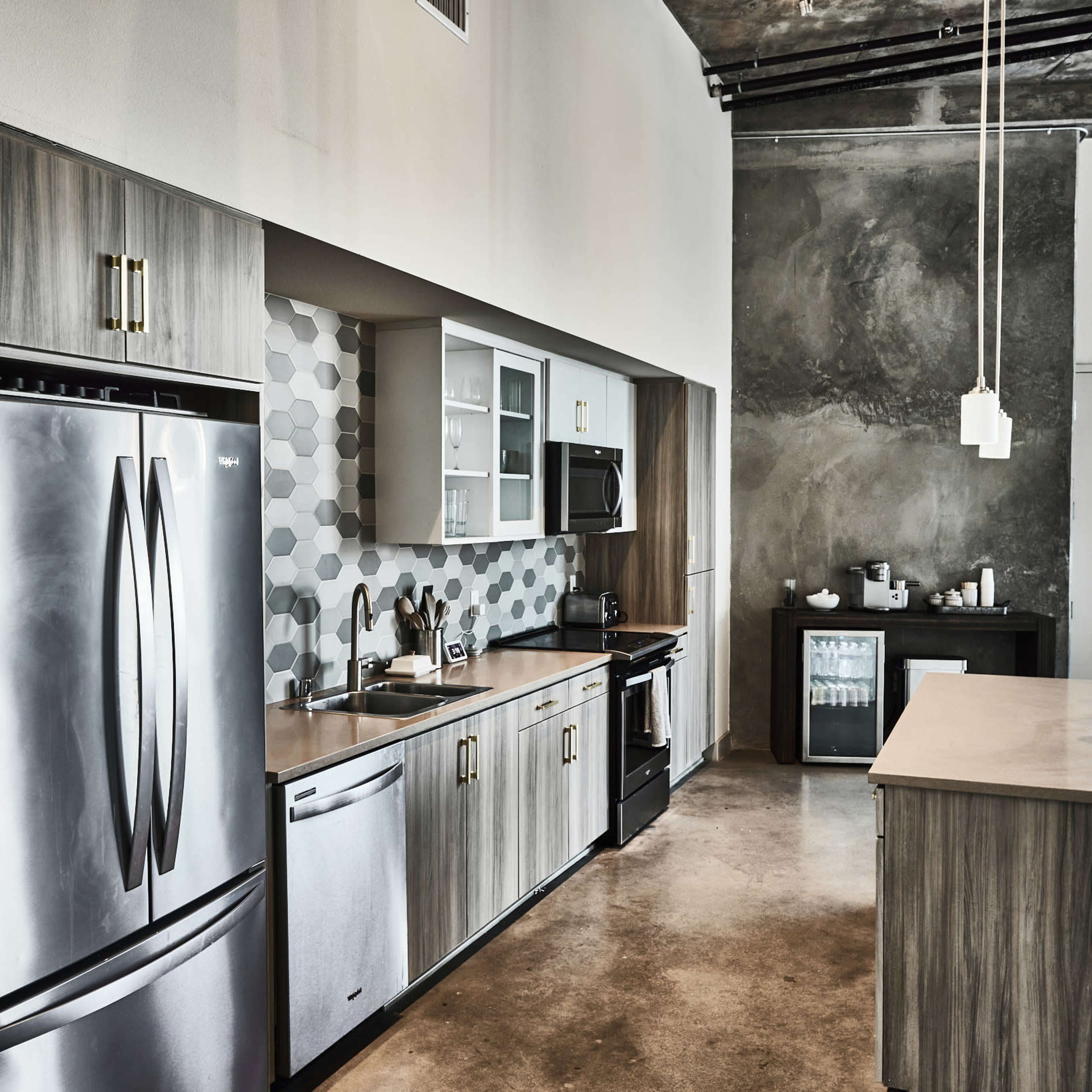 A modern kitchen with stainless steel appliances, wooden cabinetry, and a geometric backsplash.