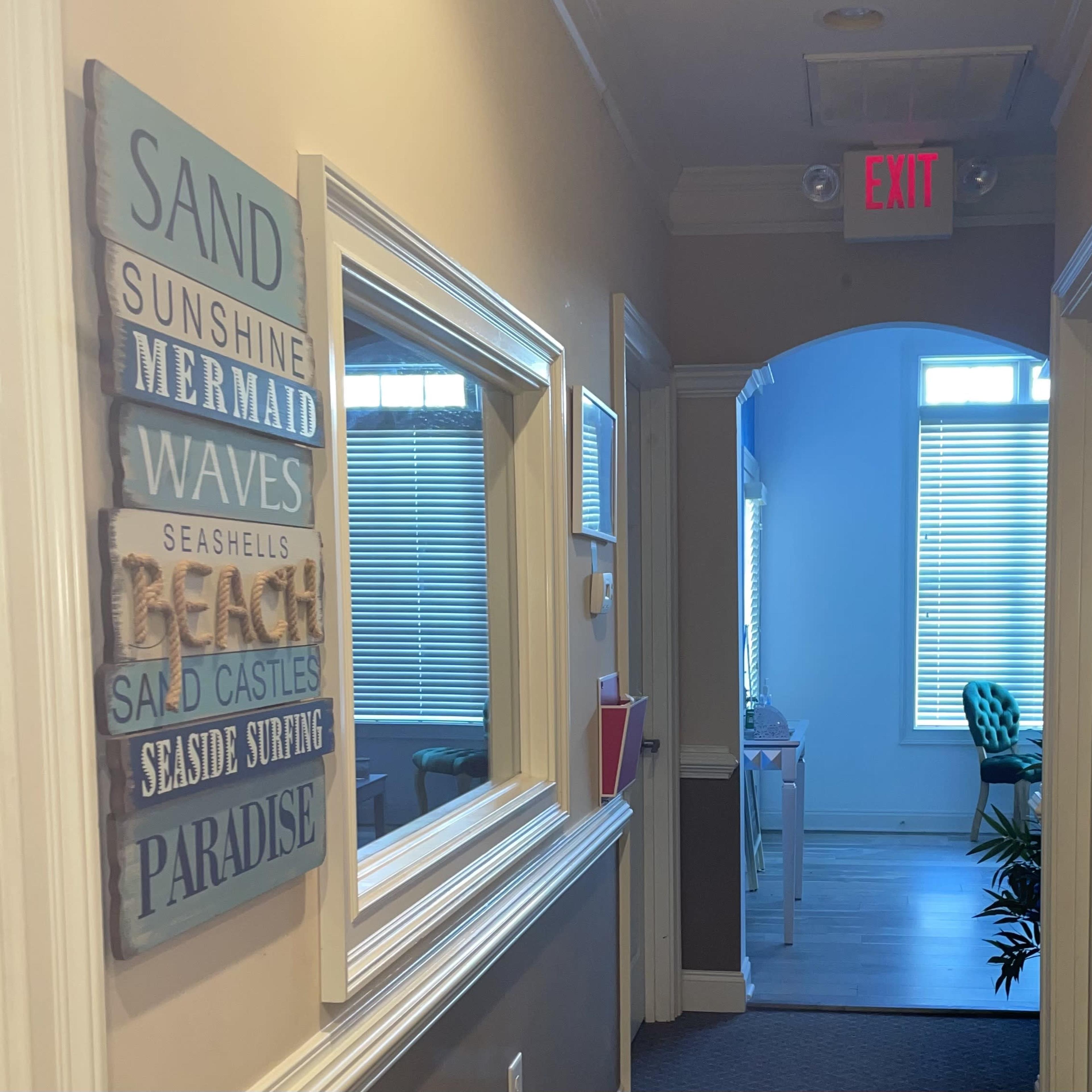 A hallway features decorative wall art and a door leading to a well-lit room at the end.