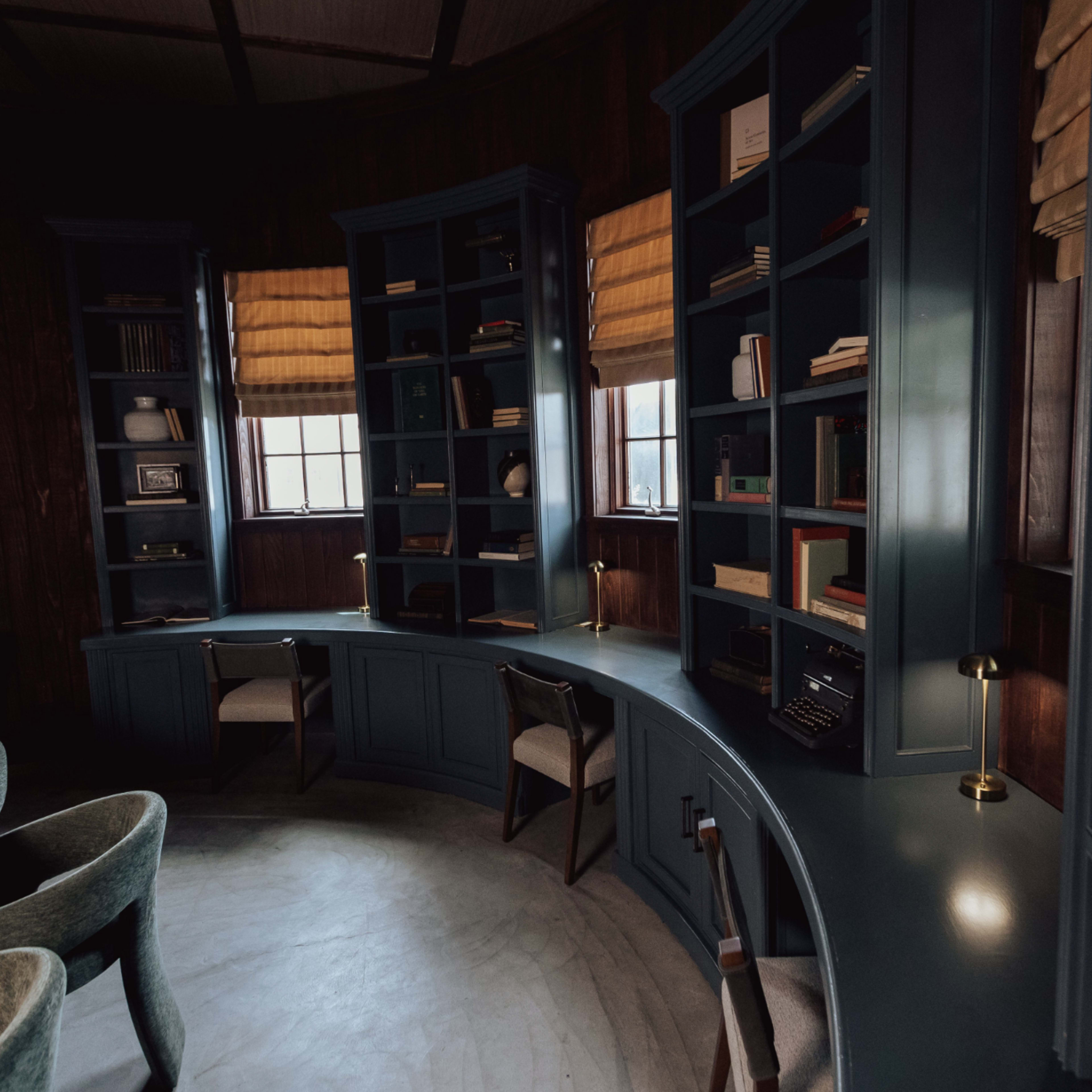 A curved desk and bookshelves filled with books in a dimly lit, circular room.
