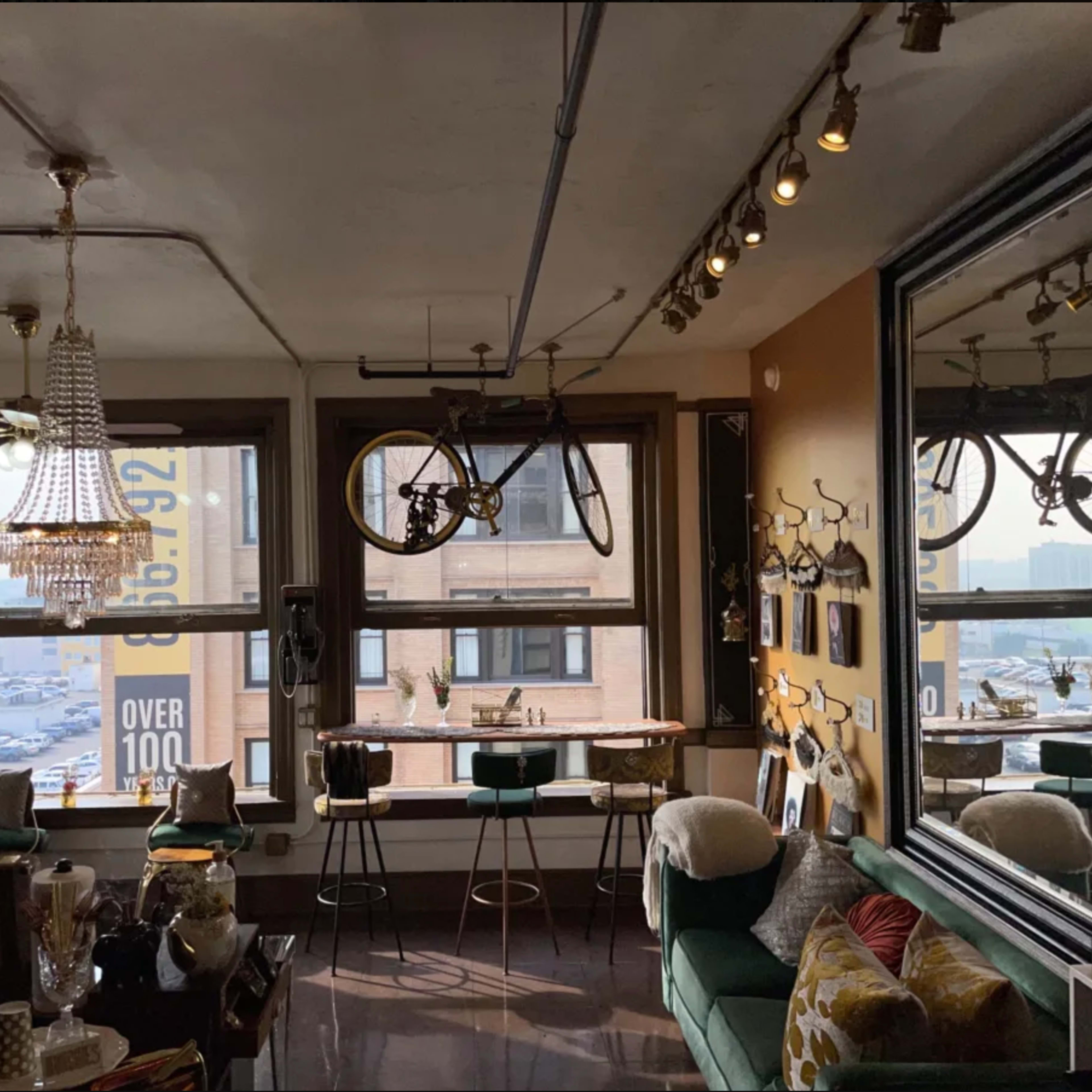 A stylishly decorated cafe with large windows, a chandelier, and bicycles mounted on the walls.