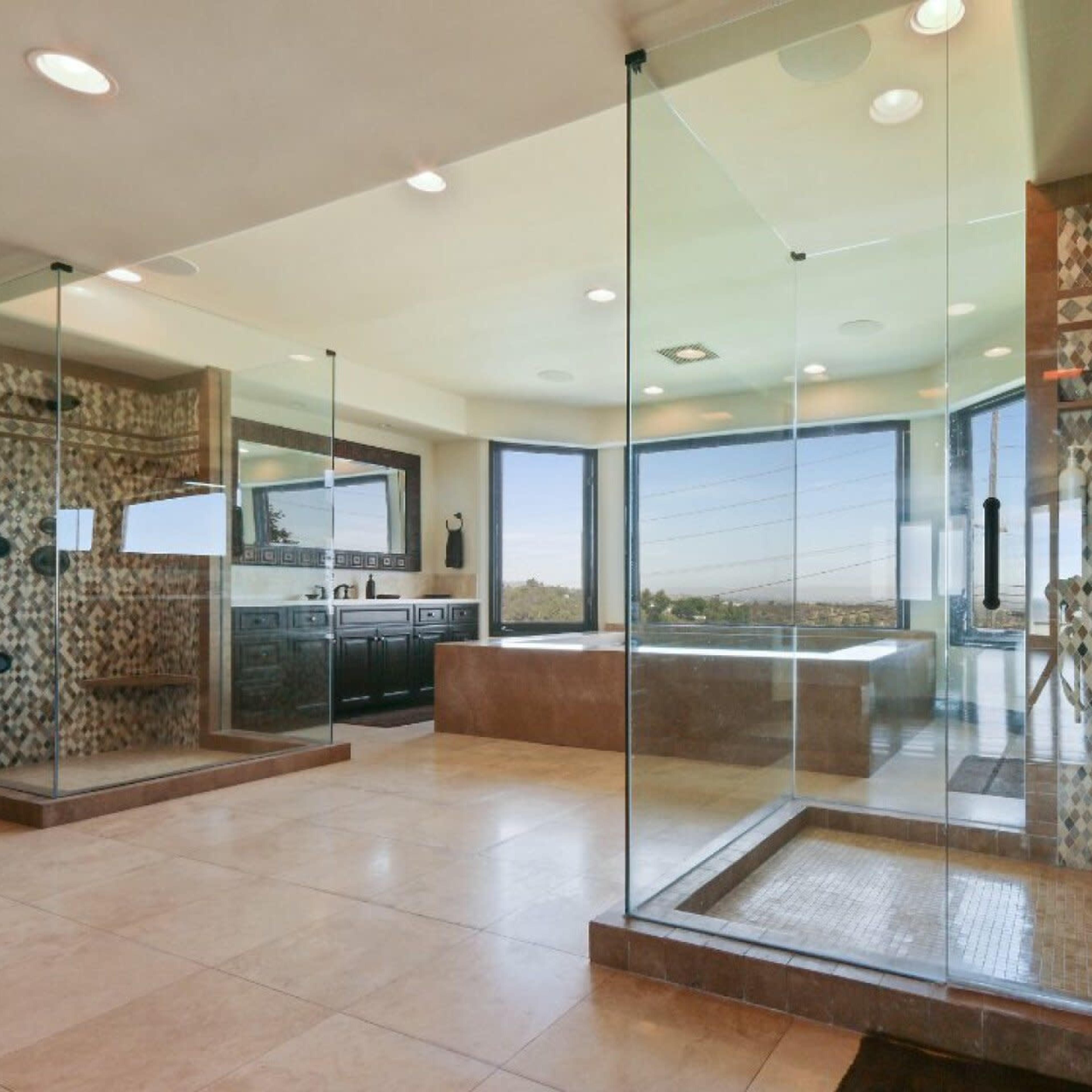 A modern bathroom featuring a spacious shower with glass walls, a freestanding bathtub, and large windows offering a scenic view.