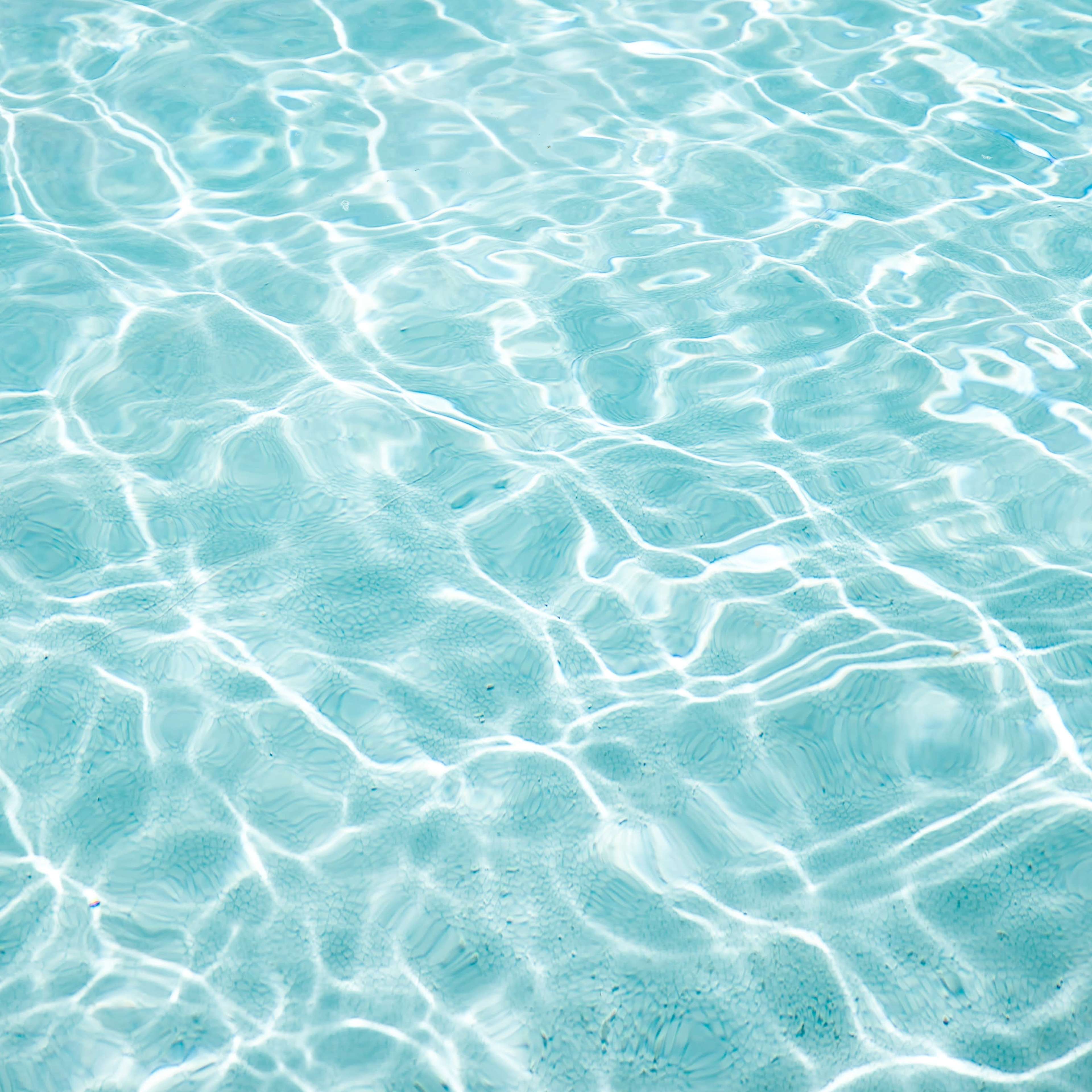 A clear, blue body of water with visible light reflections creating a rippled surface.