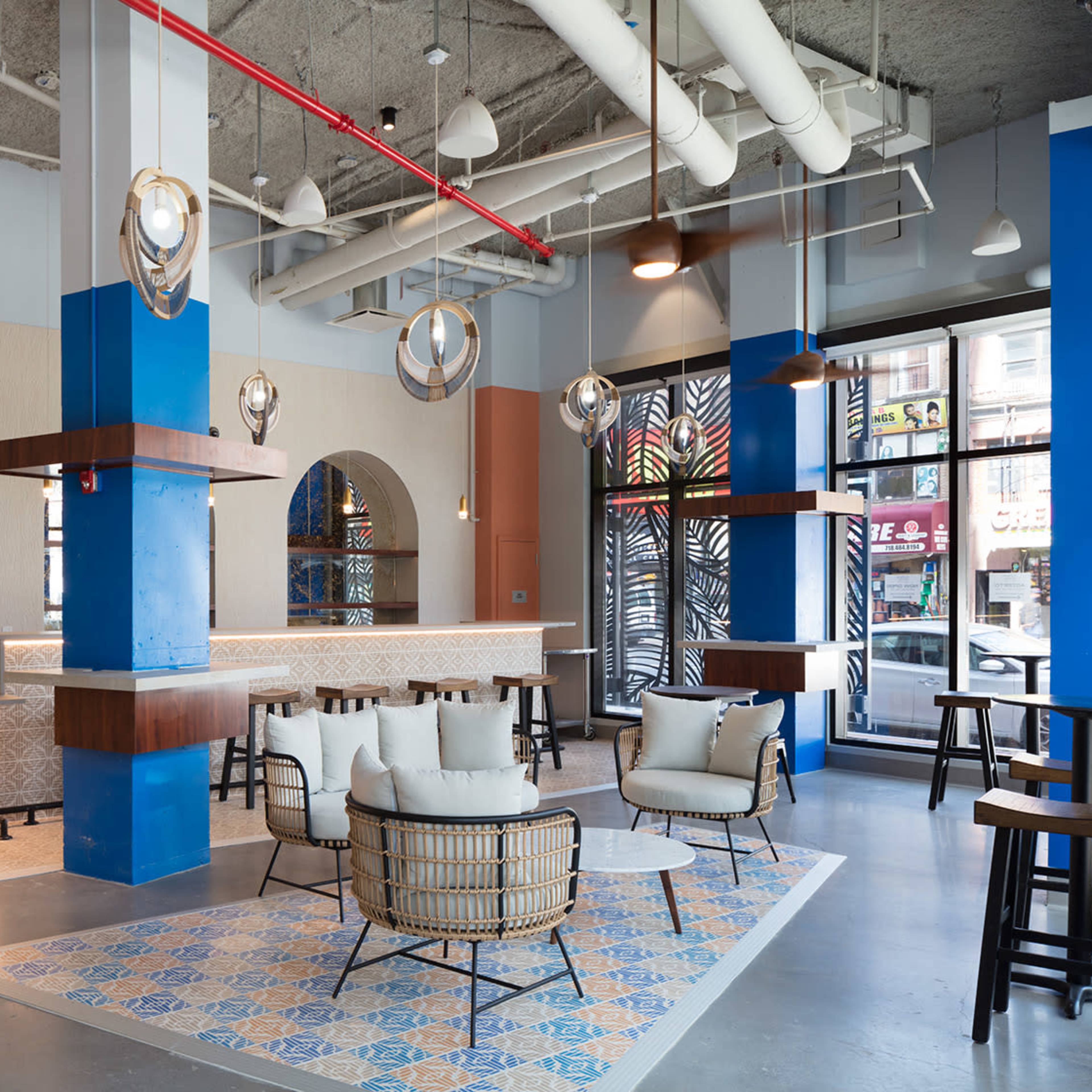 A modern, brightly lit café with a spacious layout featuring stylish seating areas, decorative arches, and hanging light fixtures.