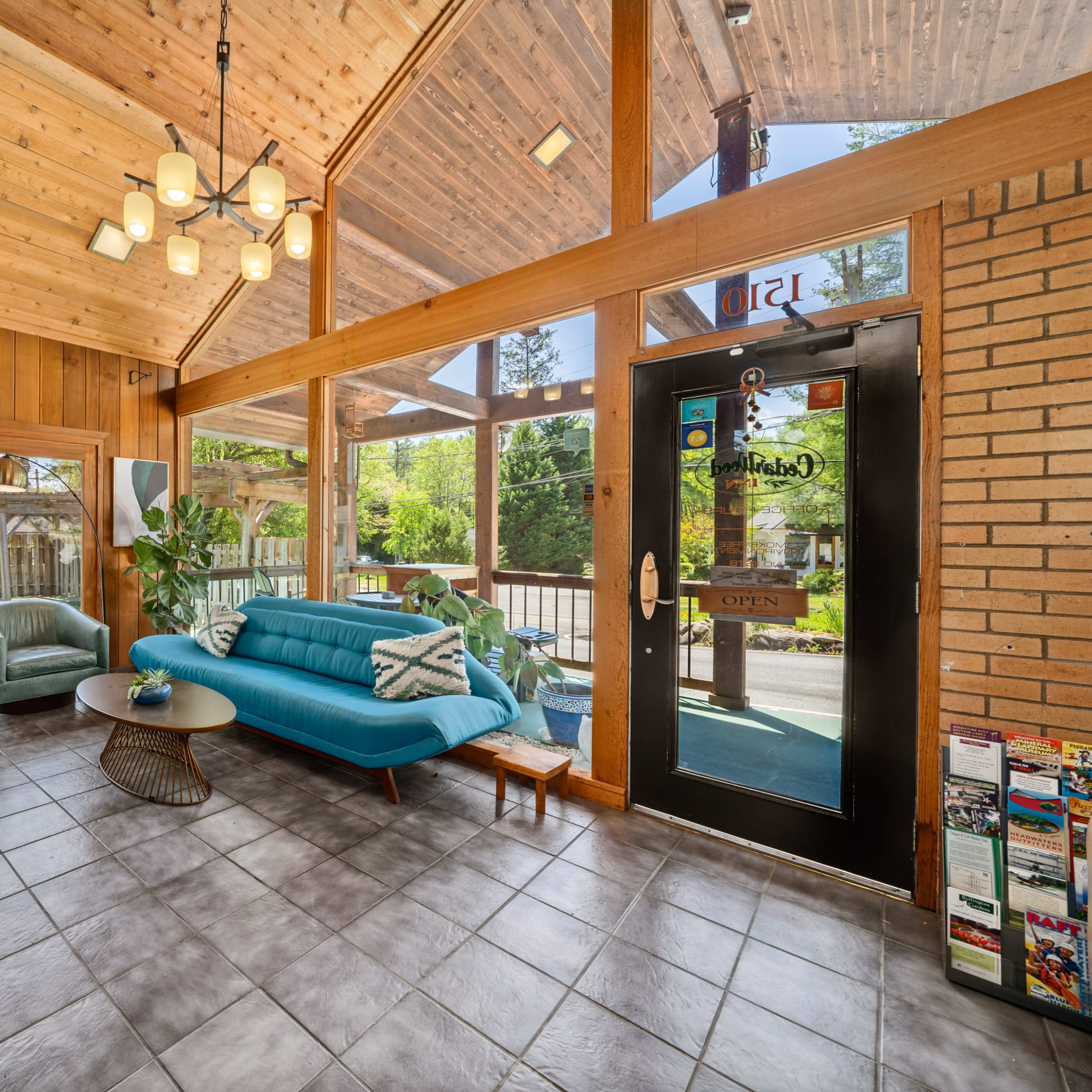 A spacious waiting area with a modern blue sofa, two green chairs, and large windows that provide natural light.