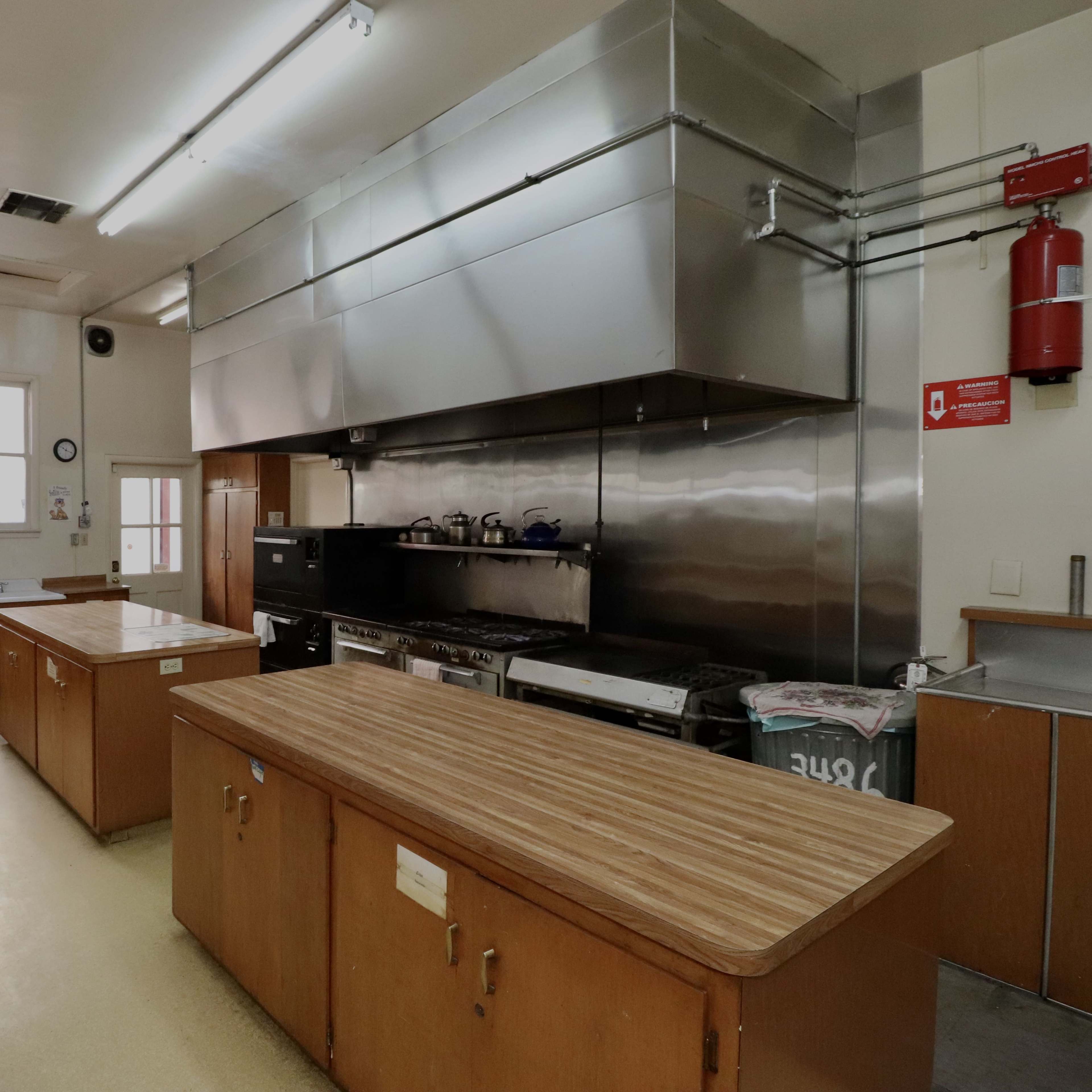 A spacious kitchen with two wooden countertops, stainless steel appliances, and ample lighting.