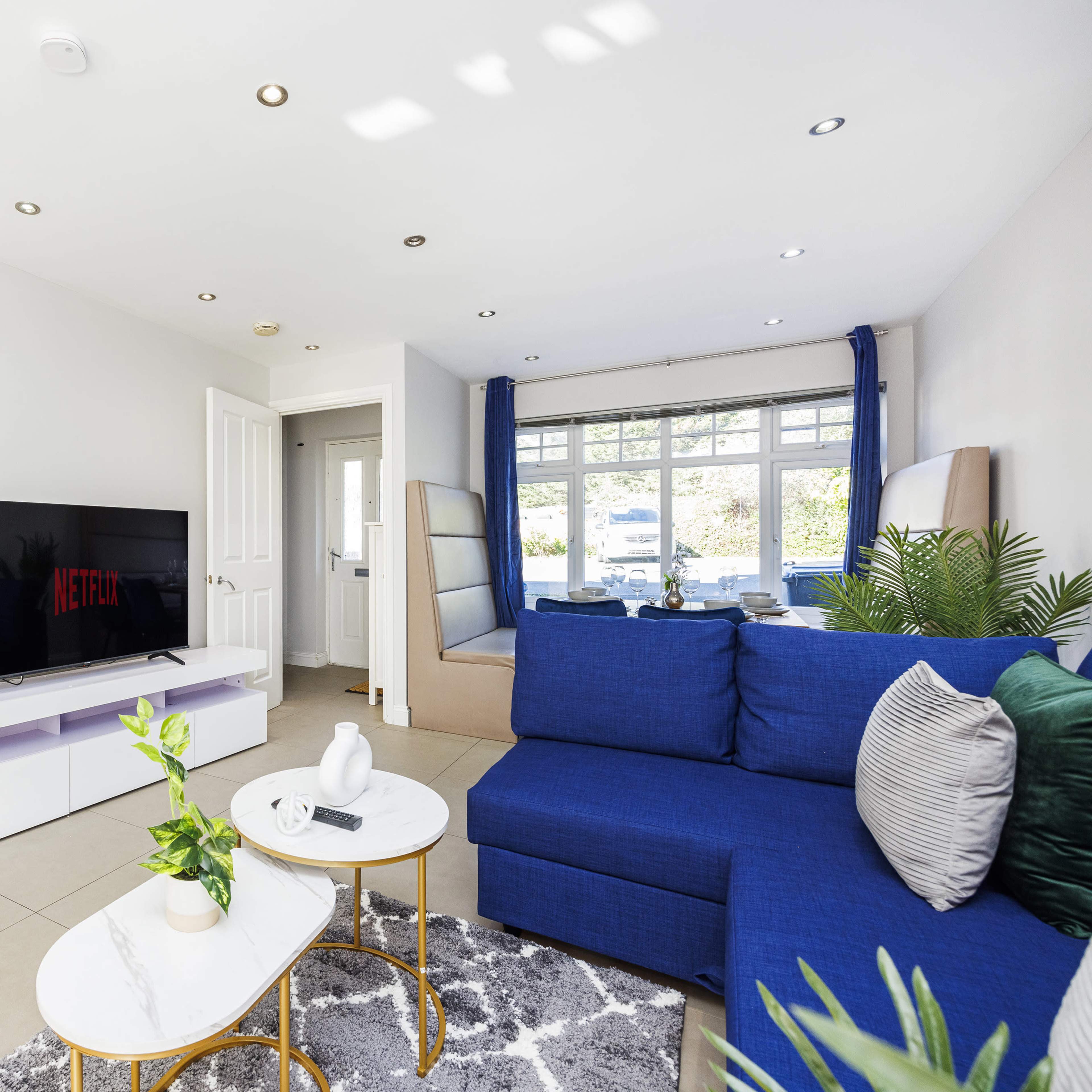 A modern living room with a blue sofa, a coffee table, and a television displaying the Netflix logo.