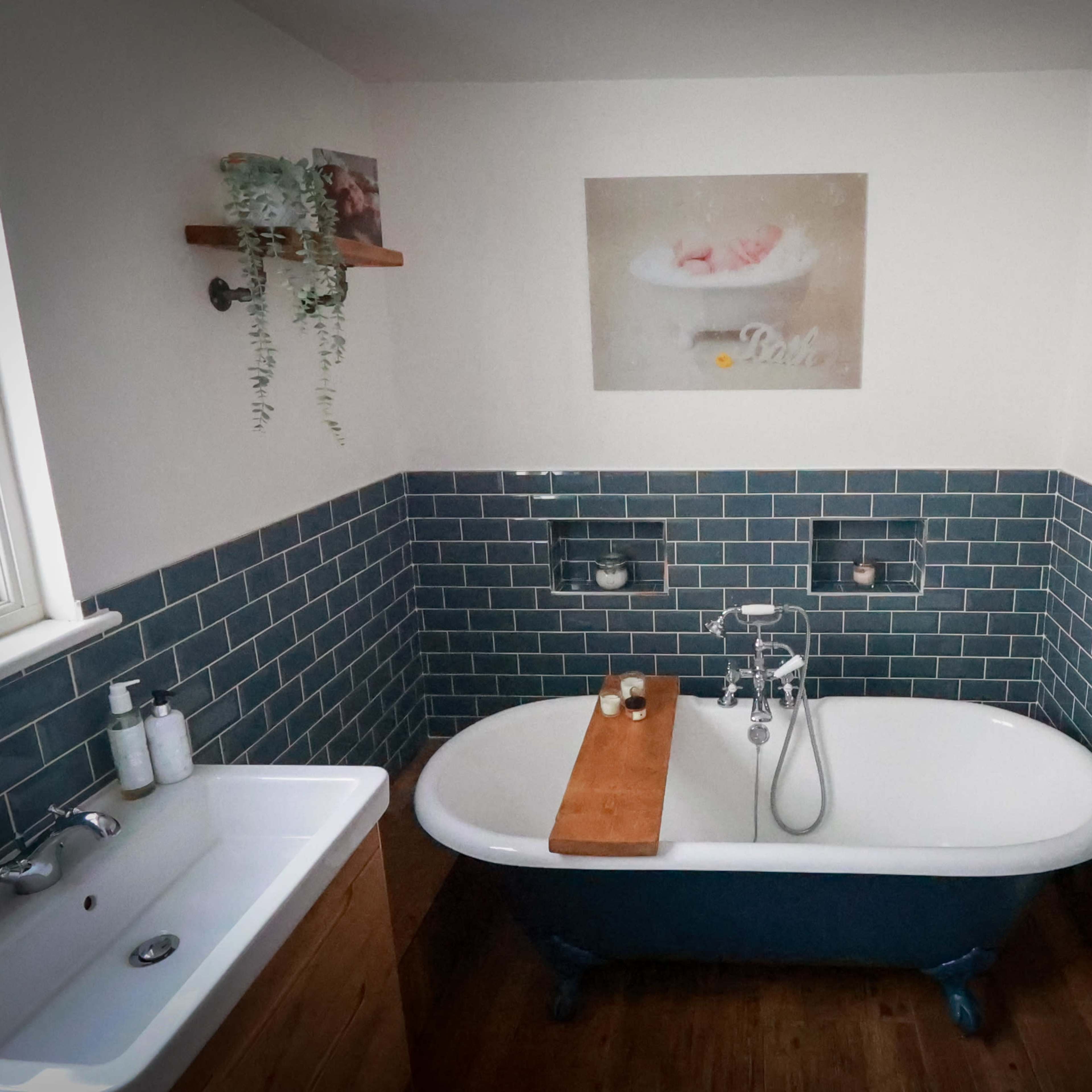 A bathroom featuring a freestanding bathtub, a wall-mounted towel warmer, and teal subway tile surrounding the space.