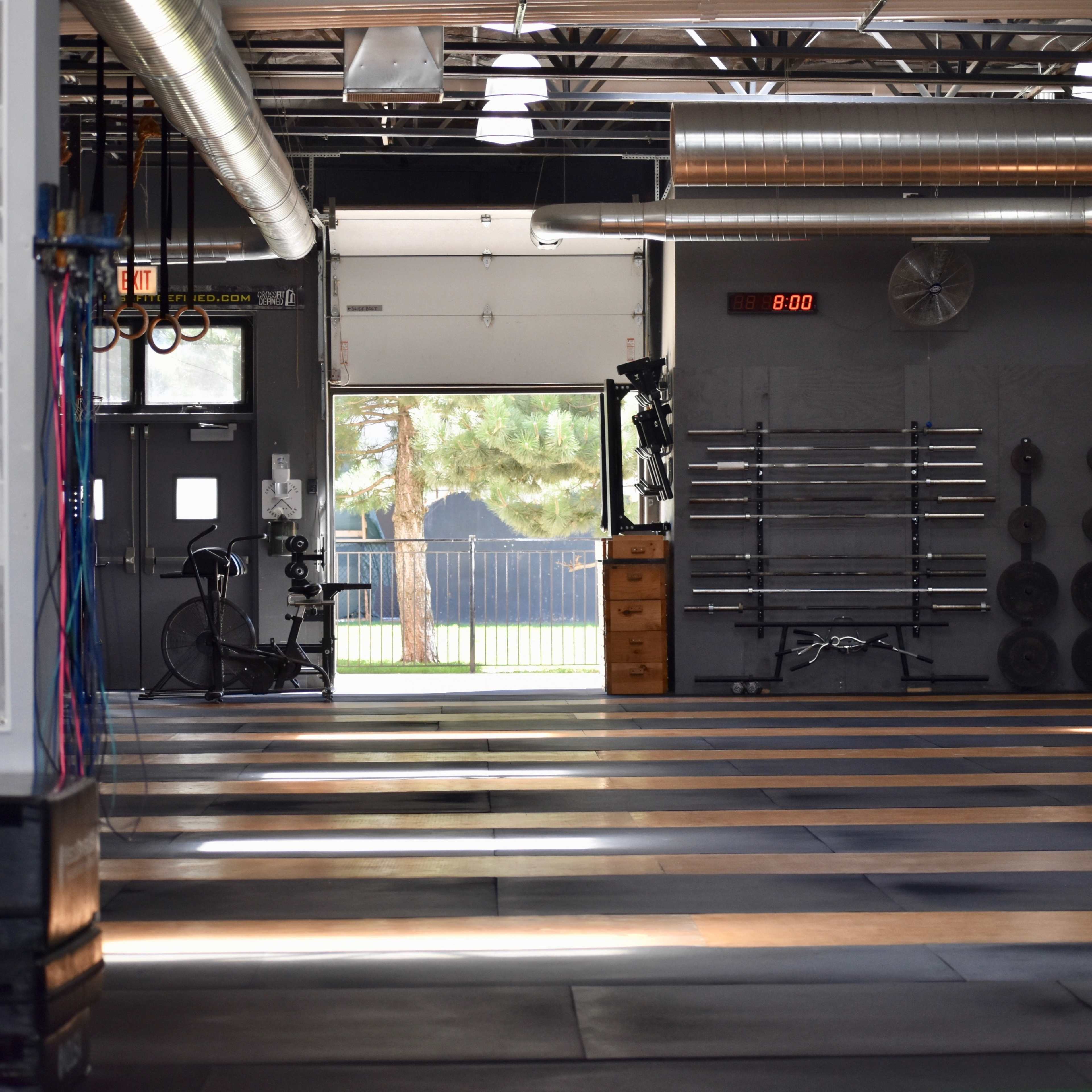 An empty gym interior with equipment storage and a large open workout area under industrial lighting.