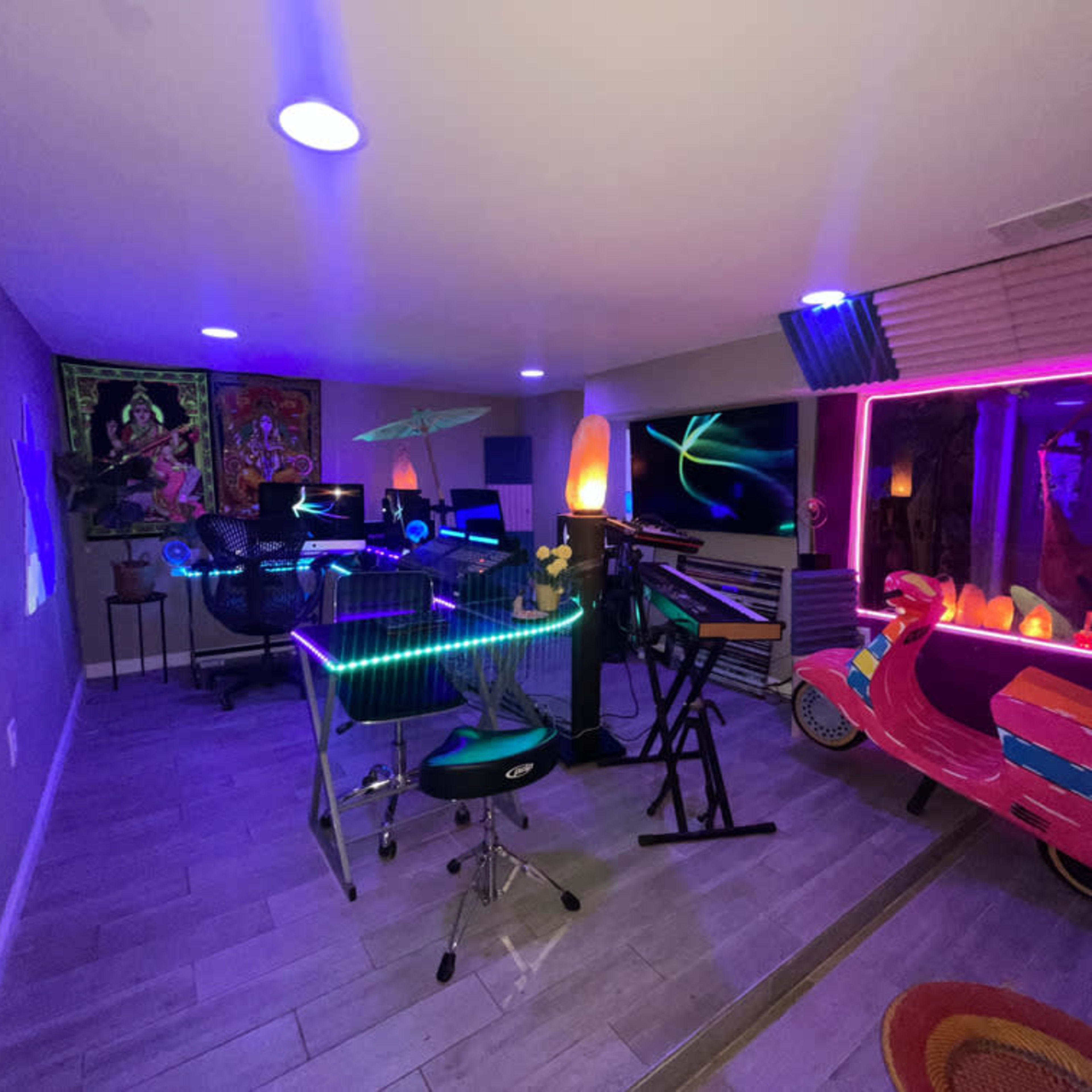 A colorful room filled with modern furniture, musical instruments, and neon lighting, including a brightly decorated vehicle.