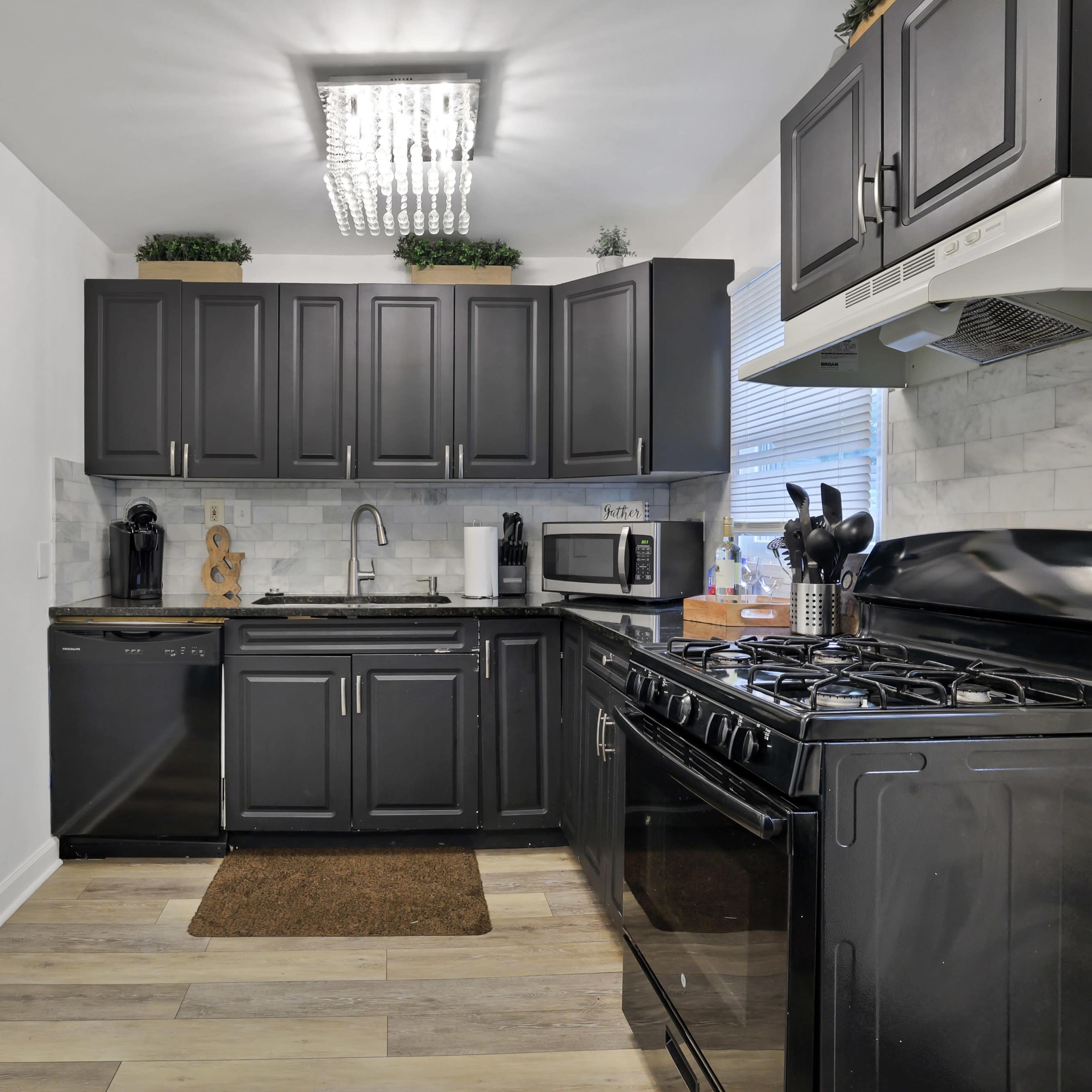 A modern kitchen with dark cabinetry, a gas stove, and stainless steel appliances.