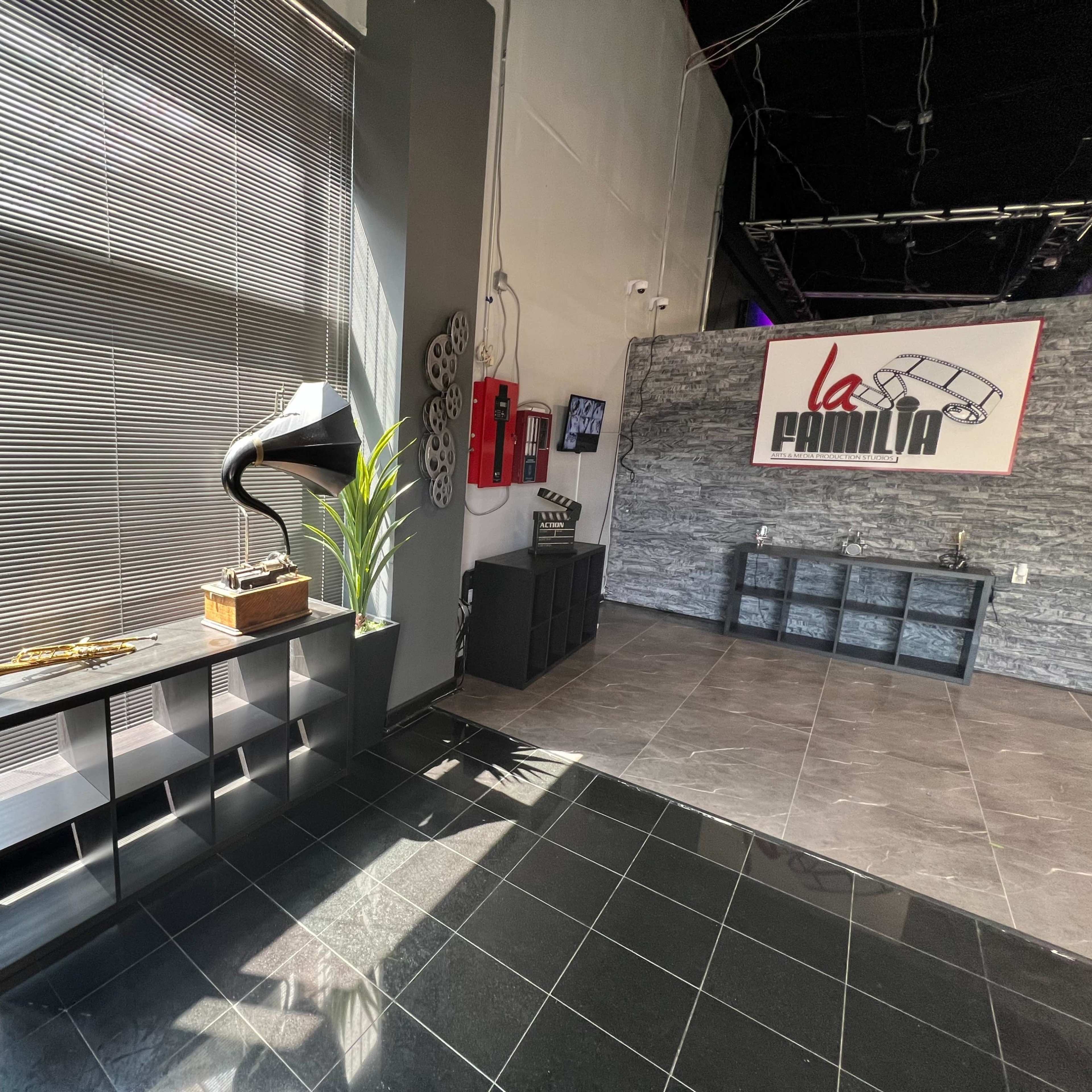 A modern reception area with a vintage gramophone on a shelf, potted plants, and a wall featuring the logo of "La Familia."